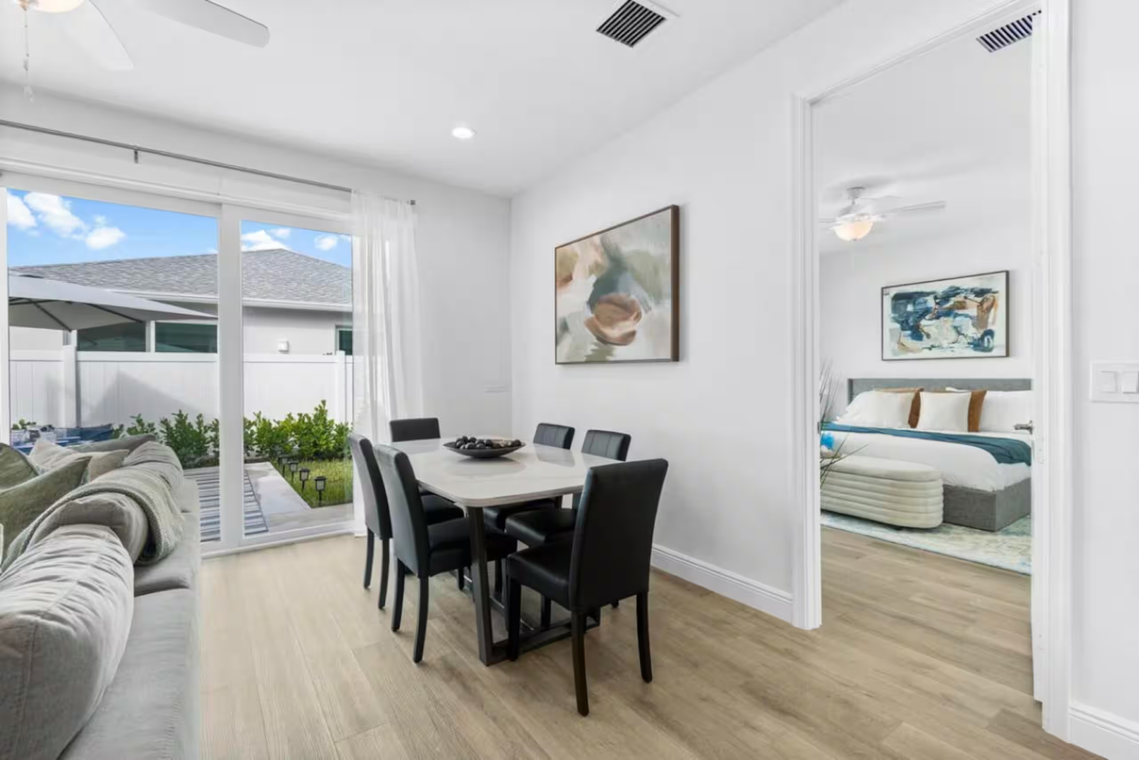 Gather around this inviting dining table for meals and conversations, with fresh air and greenery just beyond the patio doors. The open layout flows seamlessly into your cozy bedroom retreat.
