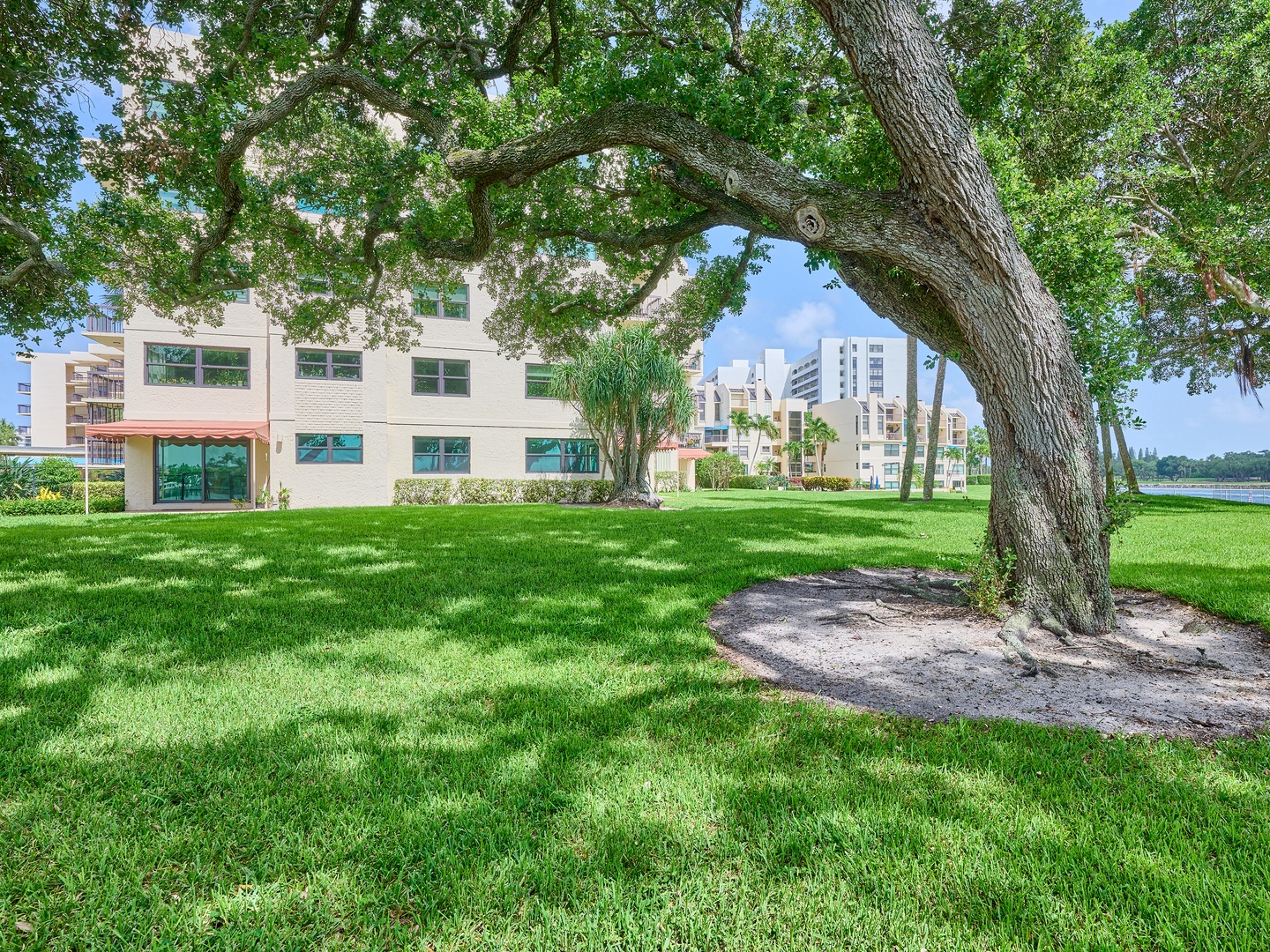 The property sits on beautifully maintained grounds with mature oak trees and lush green lawns, adjacent to a peaceful waterfront location in a quiet residential neighborhood.