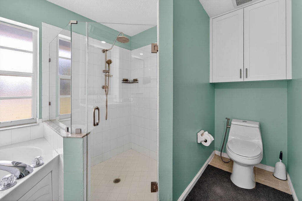 Your stylish bathroom features a spa-like glass shower, modern white fixtures, and soothing sage walls for a refreshing retreat.