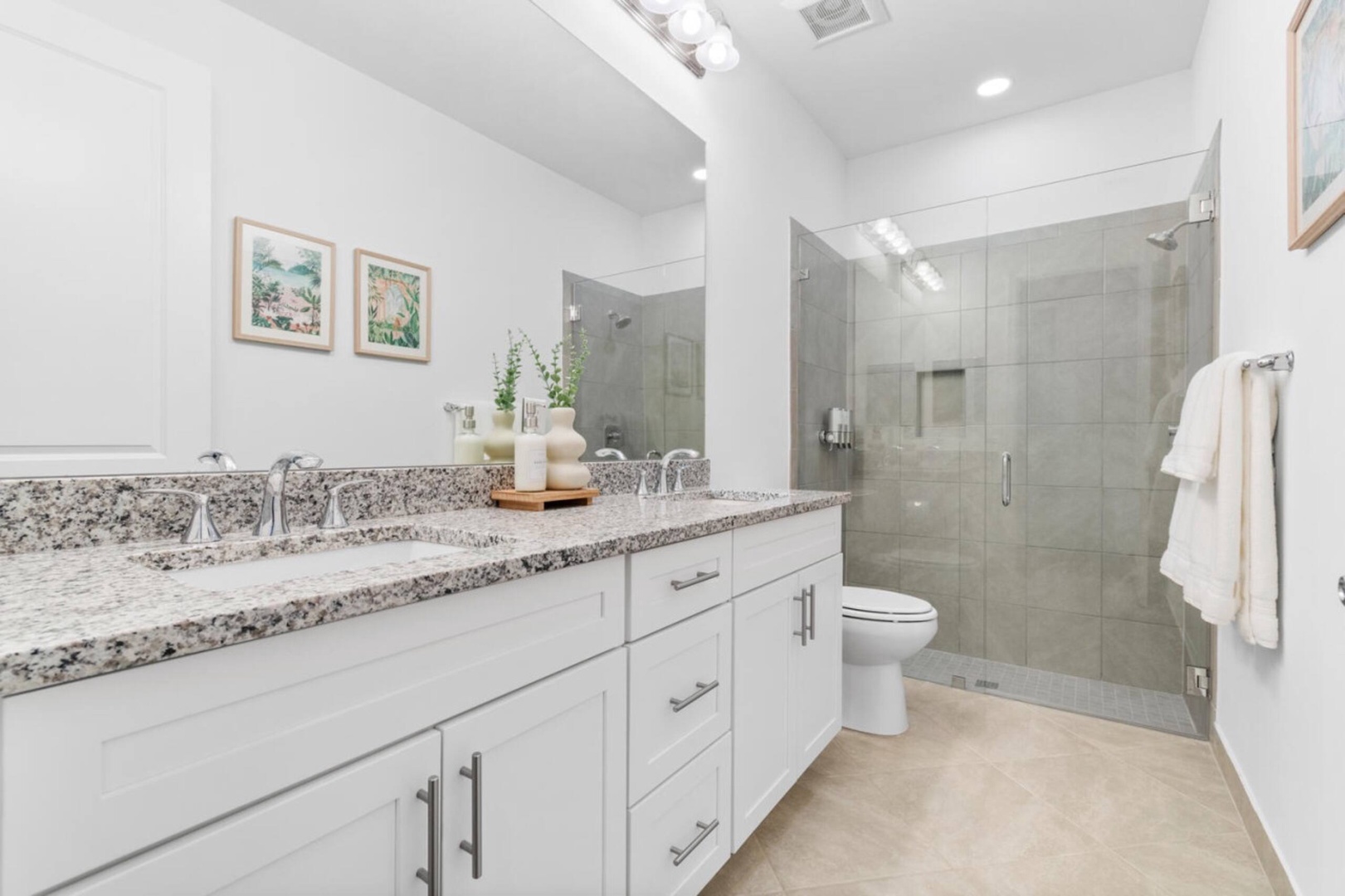 Refresh in your modern bathroom featuring a spacious granite vanity, sleek glass-enclosed shower, and crisp white finishes that create a bright, welcoming retreat.