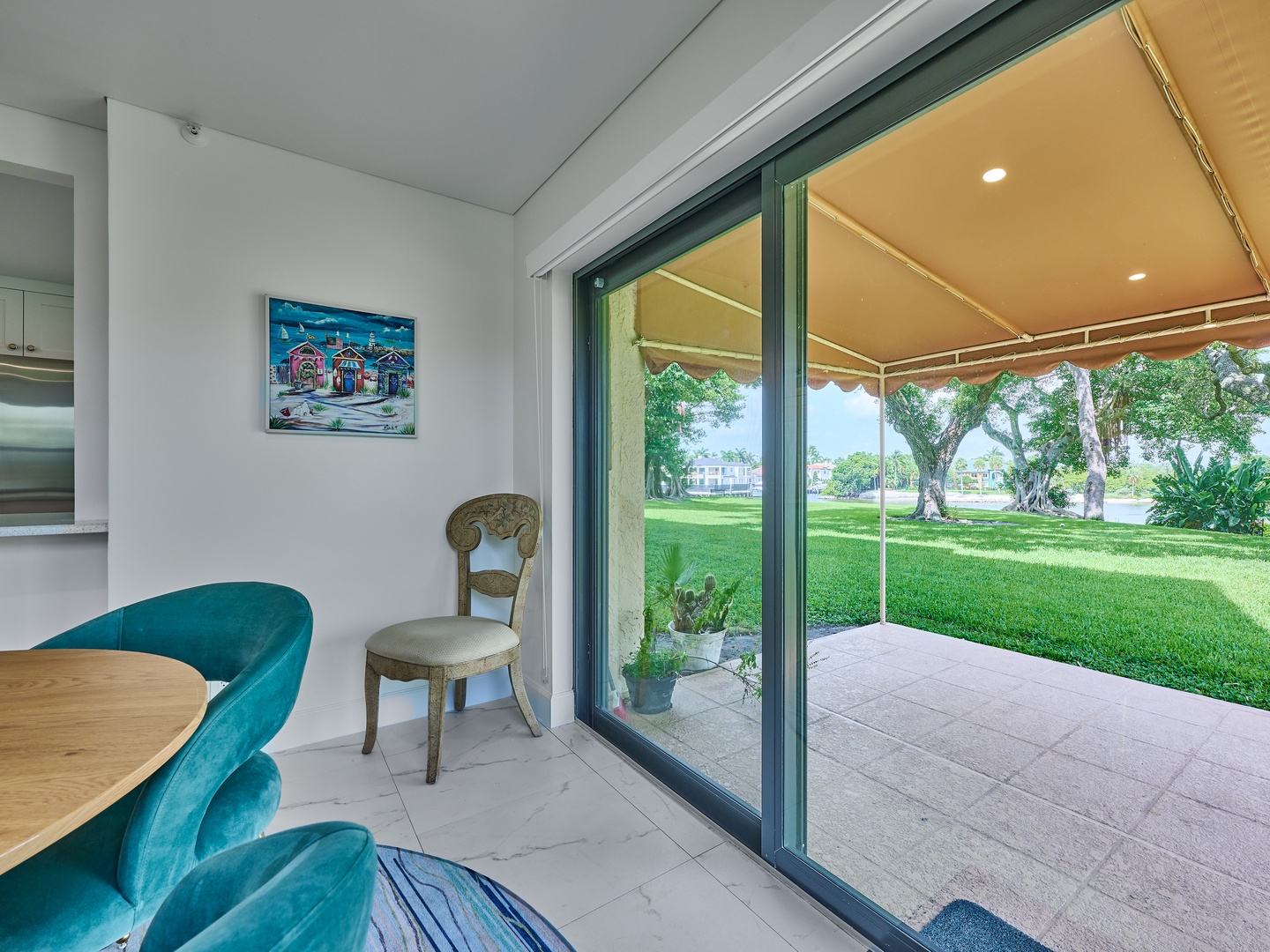 Step into your bright dining area where large glass doors open to a covered patio and sweeping views of lush lawns and mature trees—perfect for morning coffee or evening relaxation.
