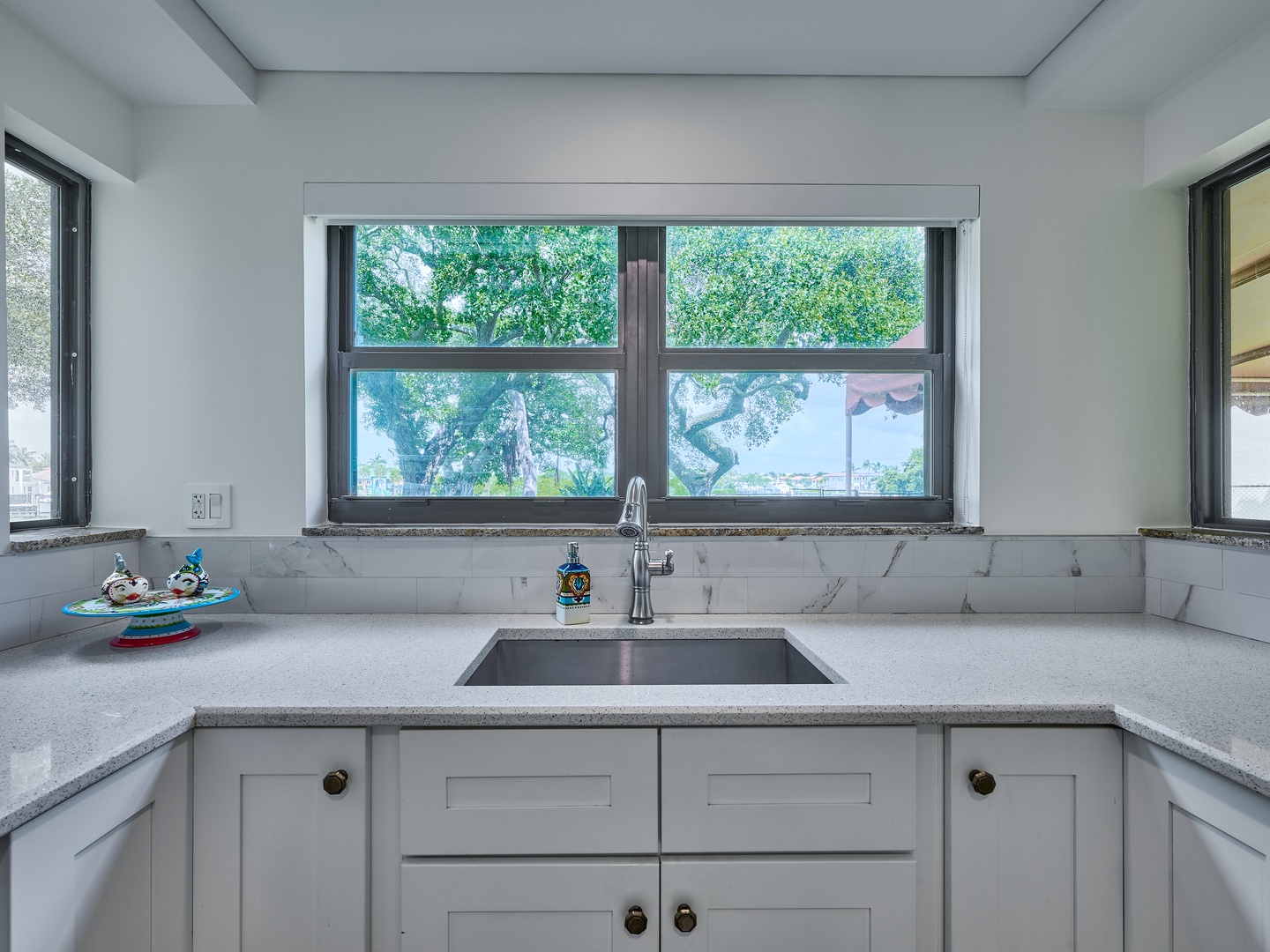 Your fully equipped kitchen features sleek countertops, a modern sink, and stunning garden views through the picture window—perfect for enjoying your morning coffee while planning the day's adventures.