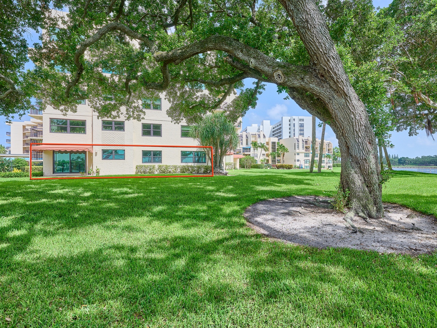 The property sits on beautifully maintained grounds with lush green lawns, mature shade trees, and a serene lake view visible in the surrounding area.
