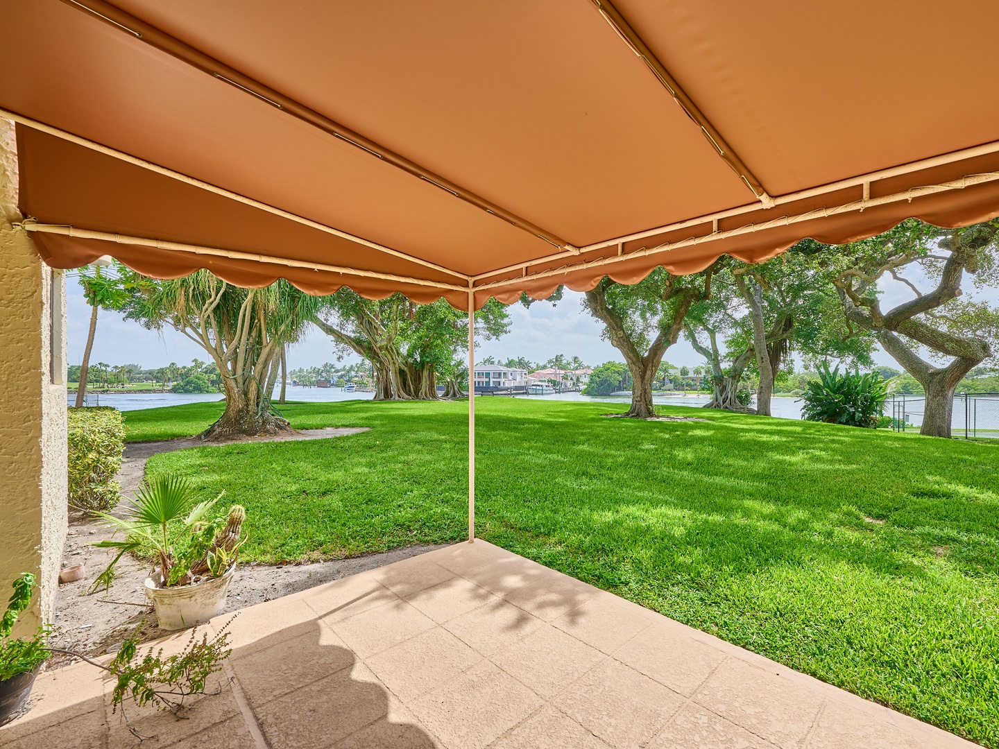 Step outside to your shaded patio and soak in sweeping waterfront views. Lush lawns stretch to the lake's edge, framed by graceful trees and distant homes across the tranquil water.