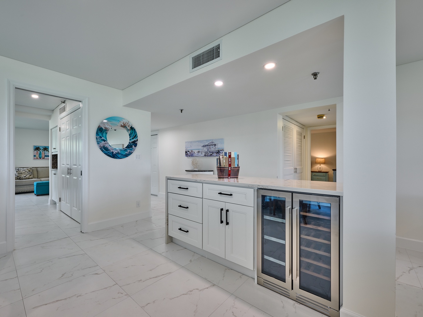 Step into your bright, open-concept space with a sleek wet bar featuring wine coolers and ample storage. The coastal-inspired décor and airy layout invite you to unwind in style.