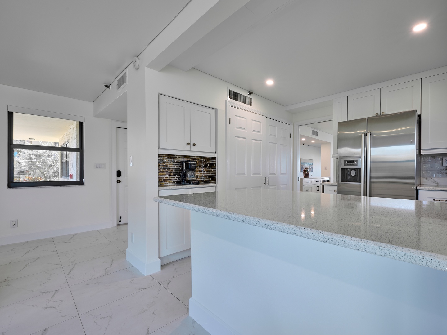 Step into your spacious, modern kitchen with sleek white cabinetry, polished stone counters, and stainless steel appliances ready for your culinary adventures.