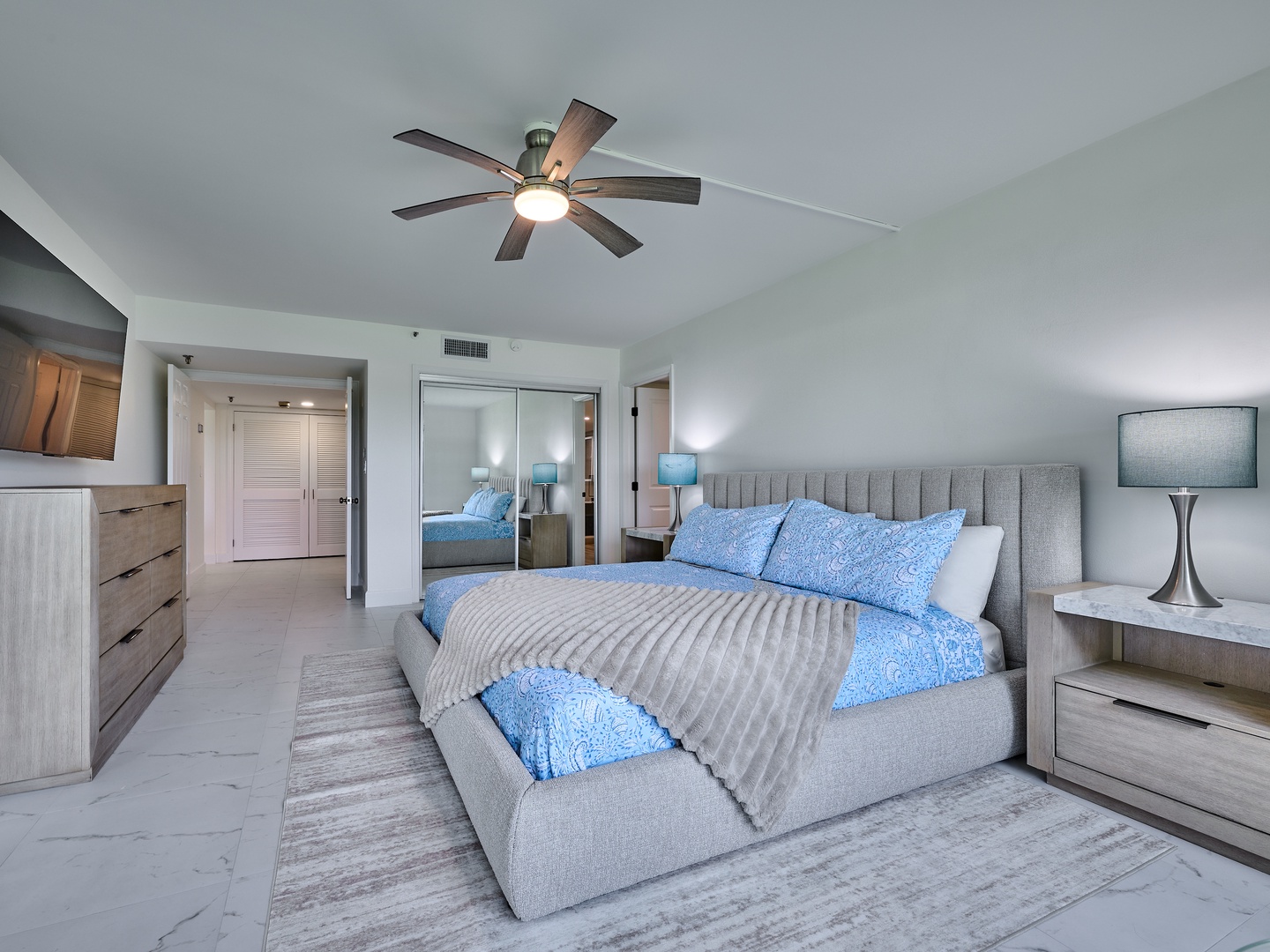 Slip into your serene retreat where soft blue linens and a plush upholstered bed invite peaceful sleep. Vaulted ceilings and a ceiling fan keep things airy, while modern nightstands offer space for your morning coffee.