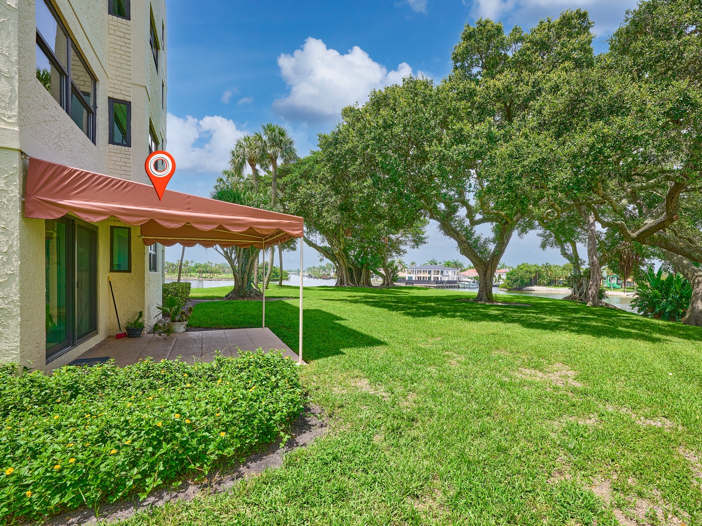 A waterfront property nestled among mature oak trees and expansive lawns, with a covered entrance leading to your ground-floor unit.