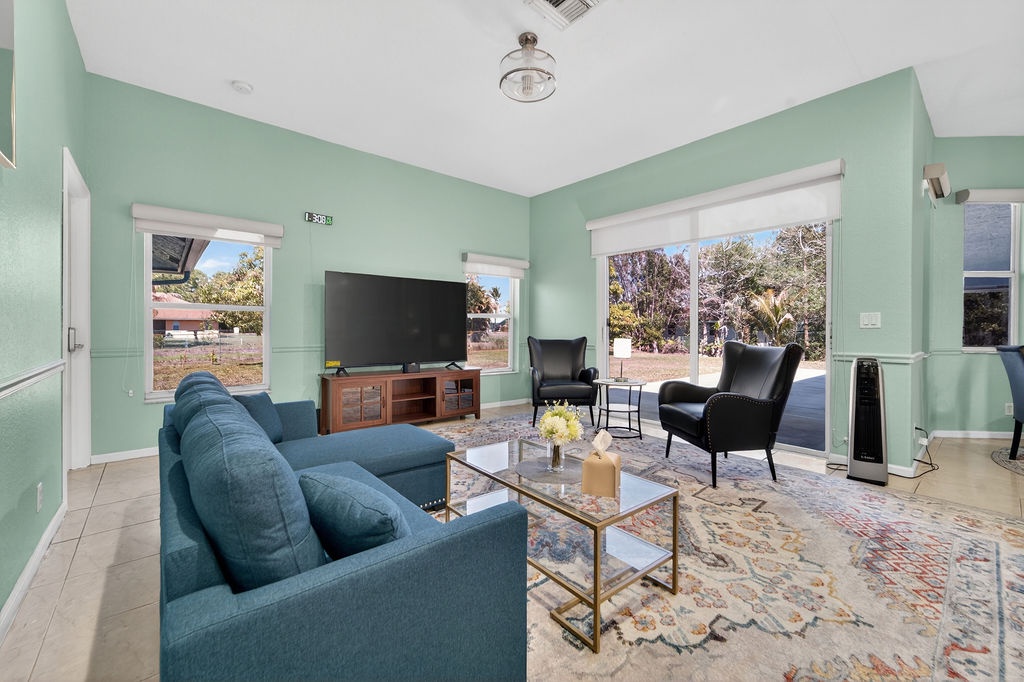 Relax in your stylish living room featuring plush turquoise seating, modern furnishings, and bright windows overlooking peaceful neighborhood views.