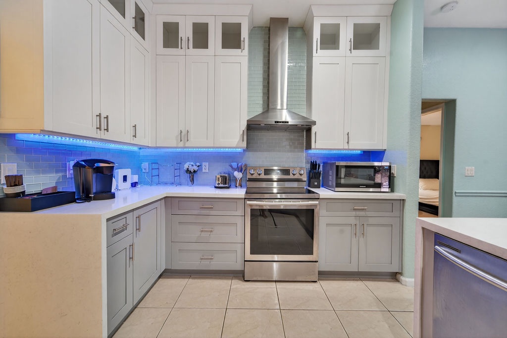 Your modern kitchen features sleek white cabinets, stainless steel appliances, and ambient blue LED lighting for effortless meal preparation.