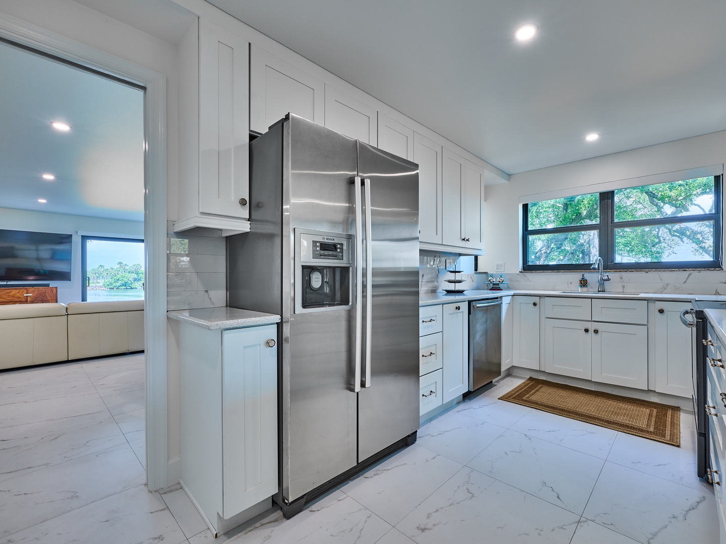Step into your bright, modern kitchen with gleaming stainless appliances and elegant white cabinetry. Natural light pours through large windows framing leafy views, making meal prep feel inspiring and relaxed.