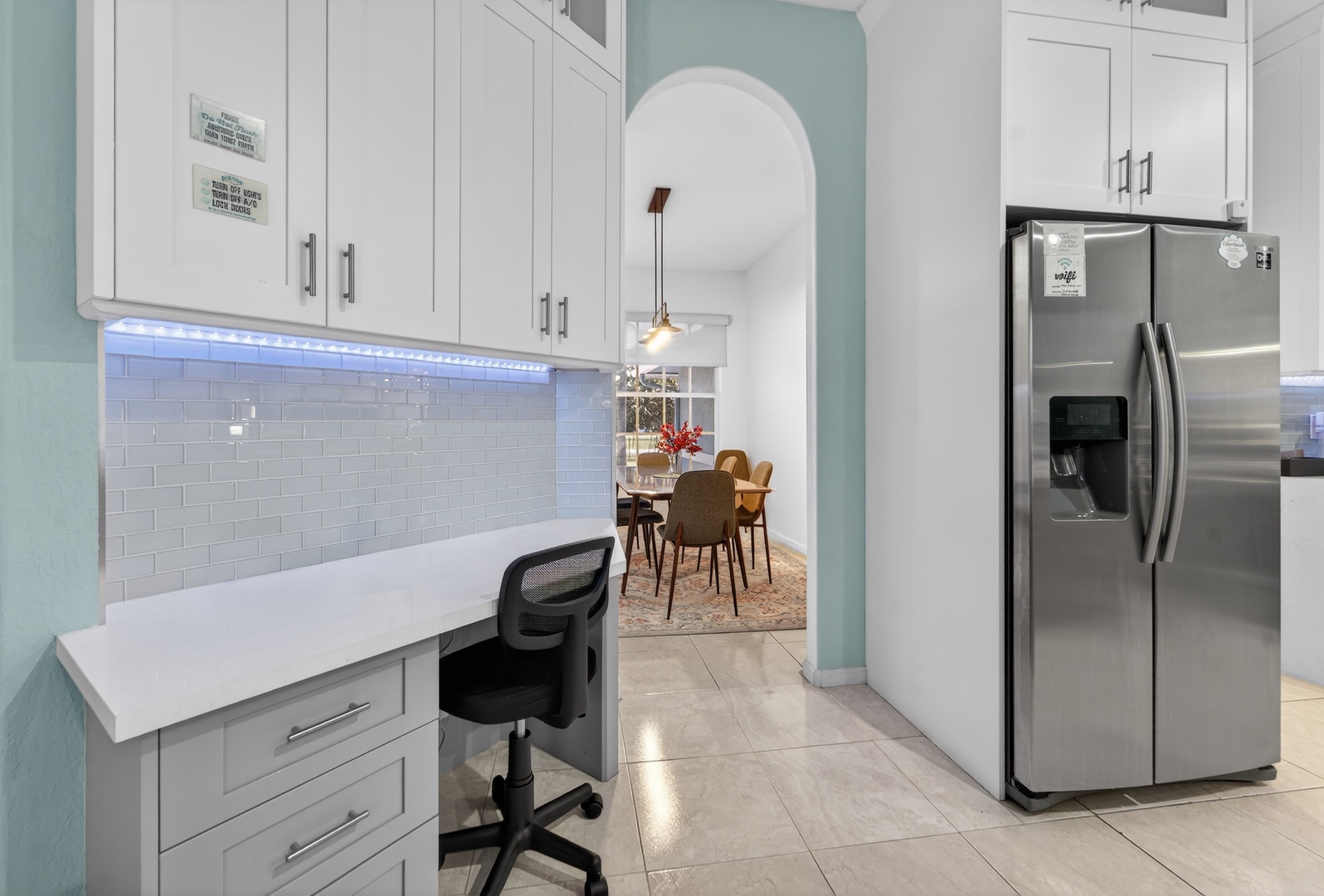 Your modern kitchen workspace features pristine white cabinets and elegant LED lighting, perfect for cooking or working from home.