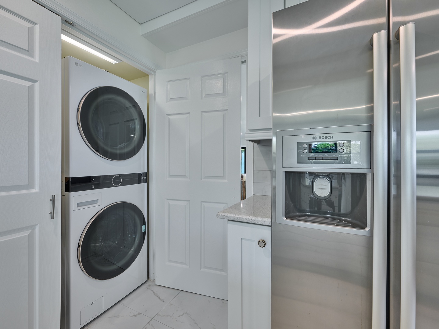 Your stay includes a well-equipped laundry area with a stacked washer and dryer for your convenience, plus a sleek stainless steel refrigerator with a built-in water and ice dispenser.