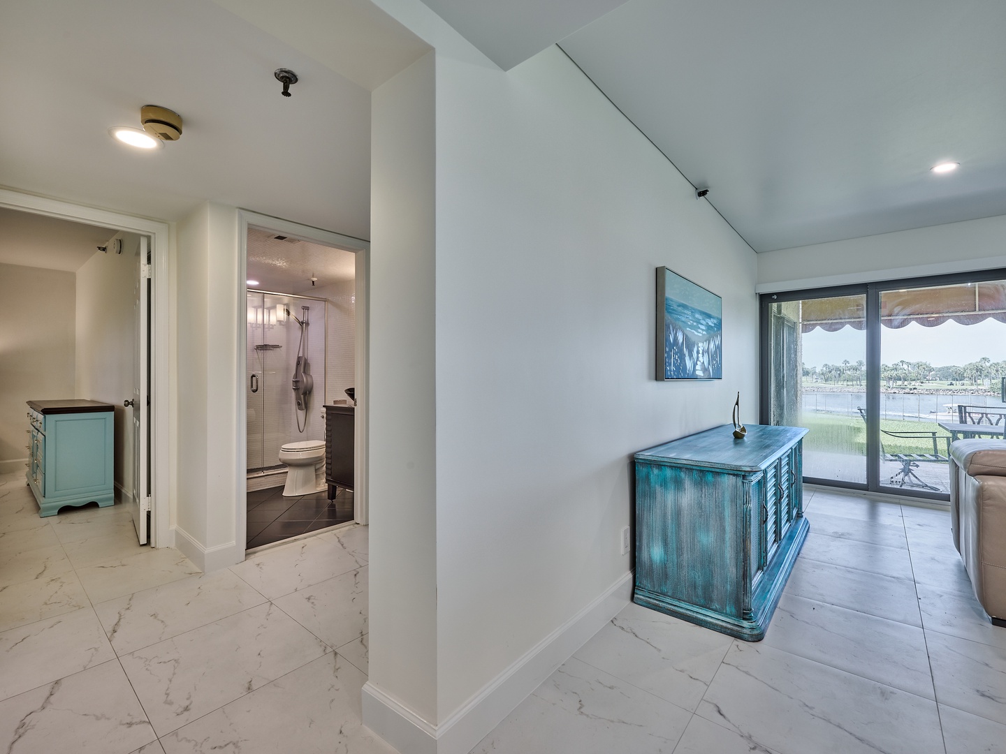 A bright, open space connects your private bathroom and living area, with waterfront views welcoming you through glass doors. The tranquil teal accents and airy layout create a seamless flow throughout your retreat.
