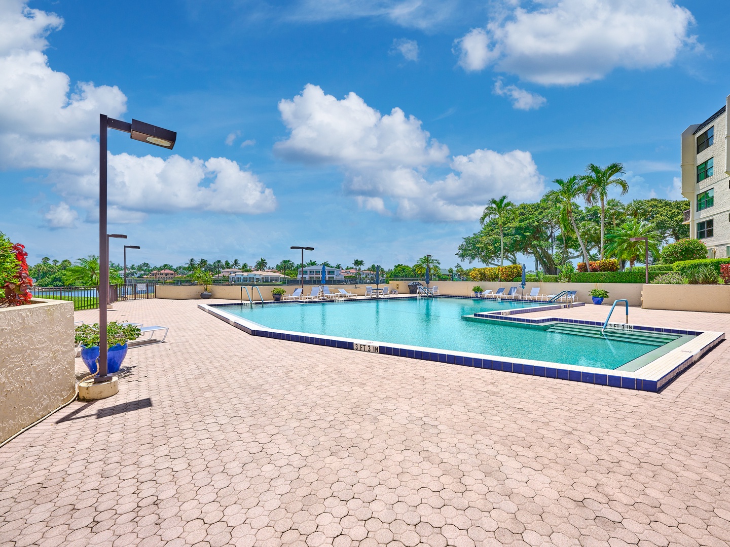 A sun-drenched pool deck with palm trees and waterfront views, offering your perfect spot to relax and soak up the Florida sunshine.