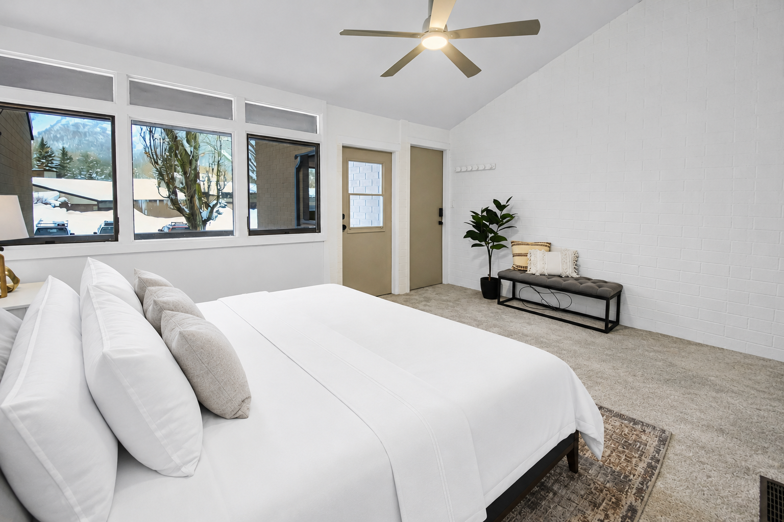 Your serene bedroom retreat awaits, featuring a plush bed beneath soaring vaulted ceilings. Drift off to sleep as natural light filters through bright windows framing peaceful mountain views.