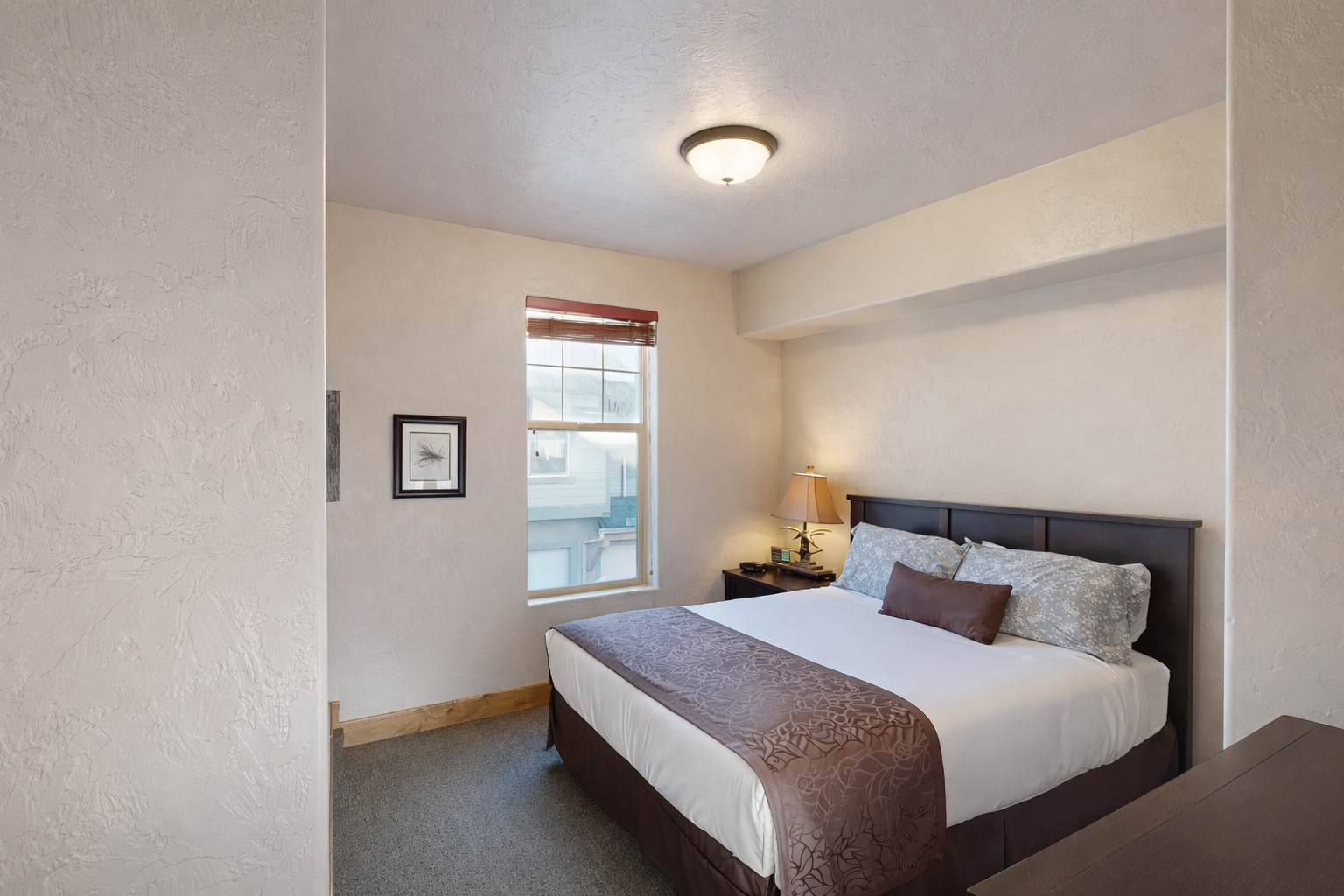 Relax in this cozy bedroom featuring a comfortable queen-size bed, nightstands with lamps, and ample closet/dresser storage space. A quiet retreat for rest and relaxation!