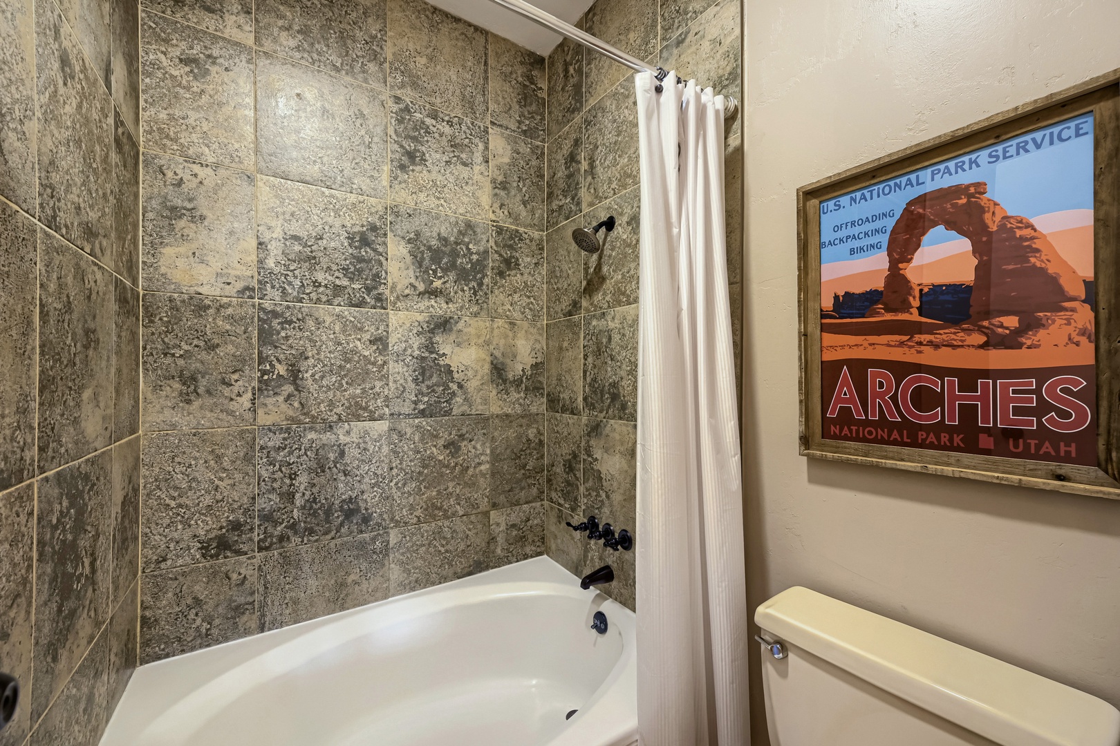 Refresh after your adventures in this modern bathroom featuring a tub-shower combo, stone-look tile surround, and National Park-inspired décor to remind you of the natural wonders just outside your door.