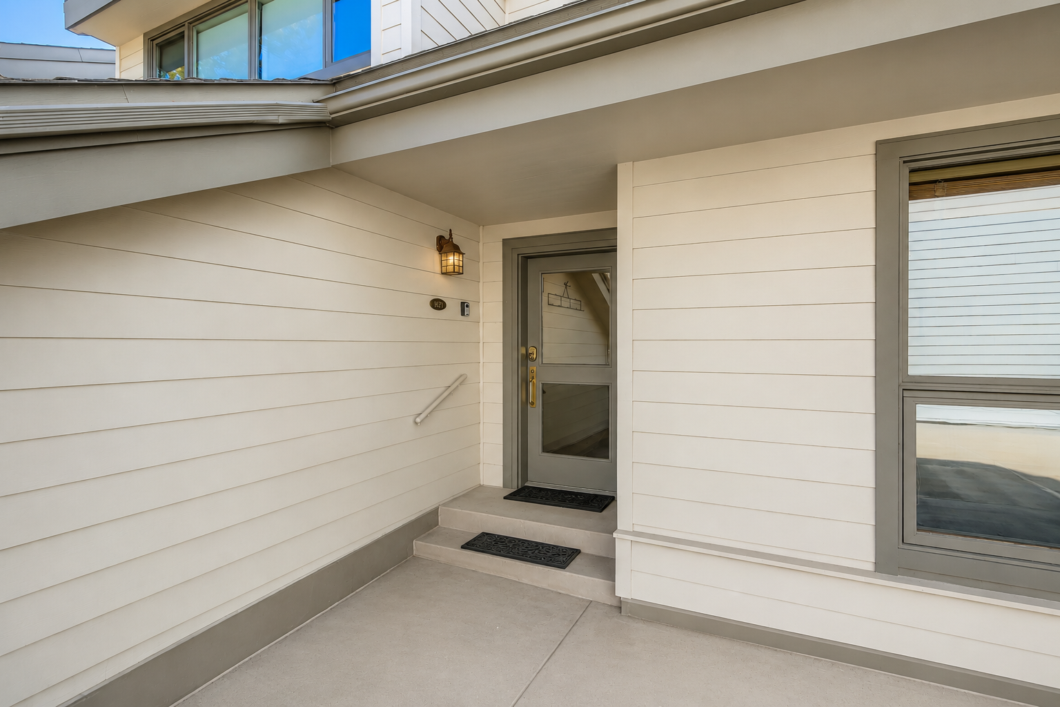 The property entrance features a modern gray door with shiplap siding and covered porch area.