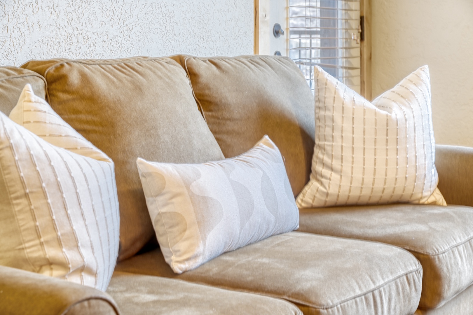 Sink into plush cushions and soft throw pillows on your comfortable living room sofa, where natural light creates the perfect spot to unwind.