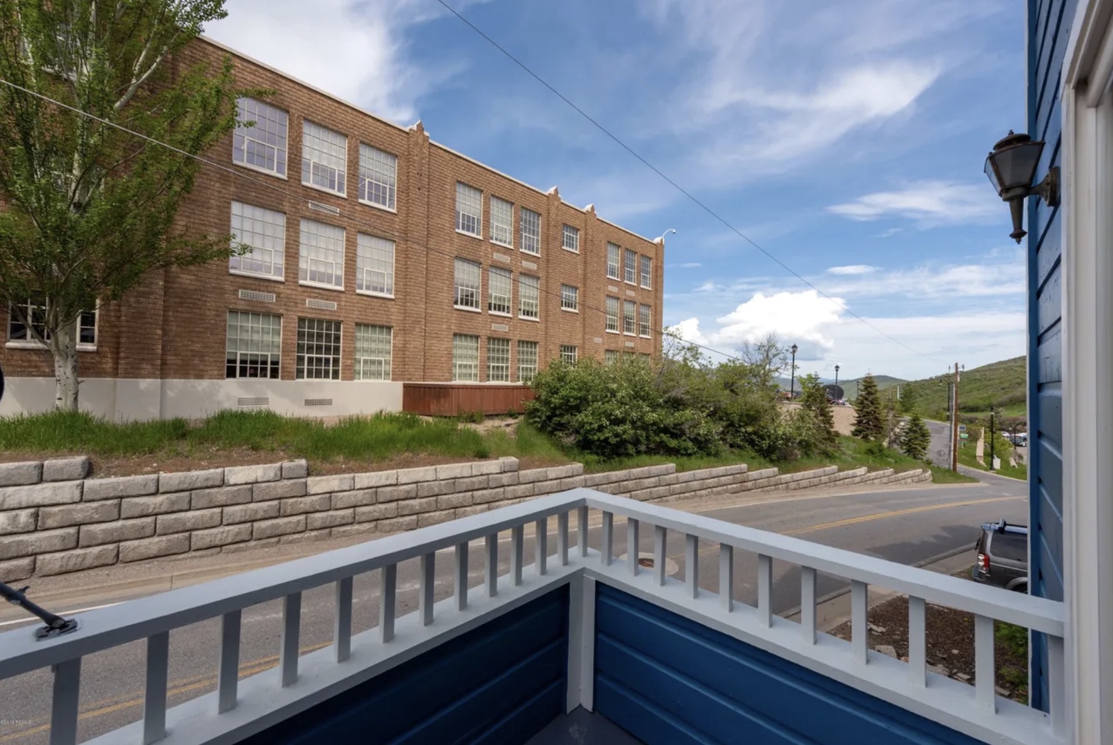 A peaceful balcony overlooks a charming historic brick building and quiet neighborhood streets, perfect for morning coffee or evening relaxation.