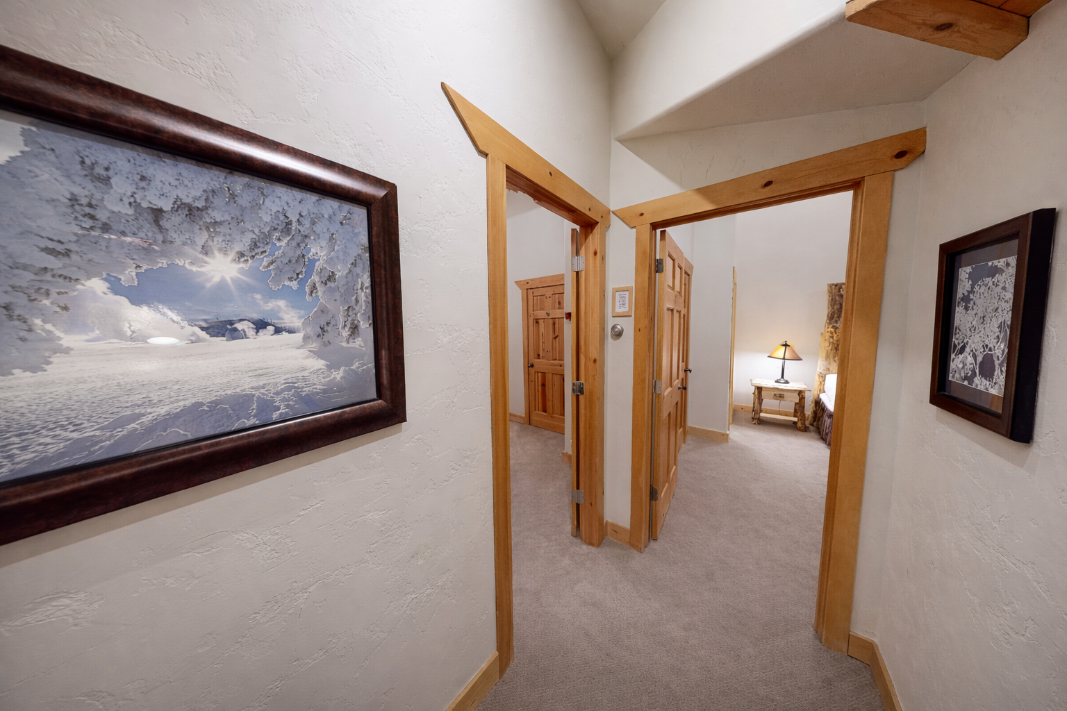 Your private hallway features warm wood accents and mountain photography, leading you to cozy bedrooms for peaceful rest.
