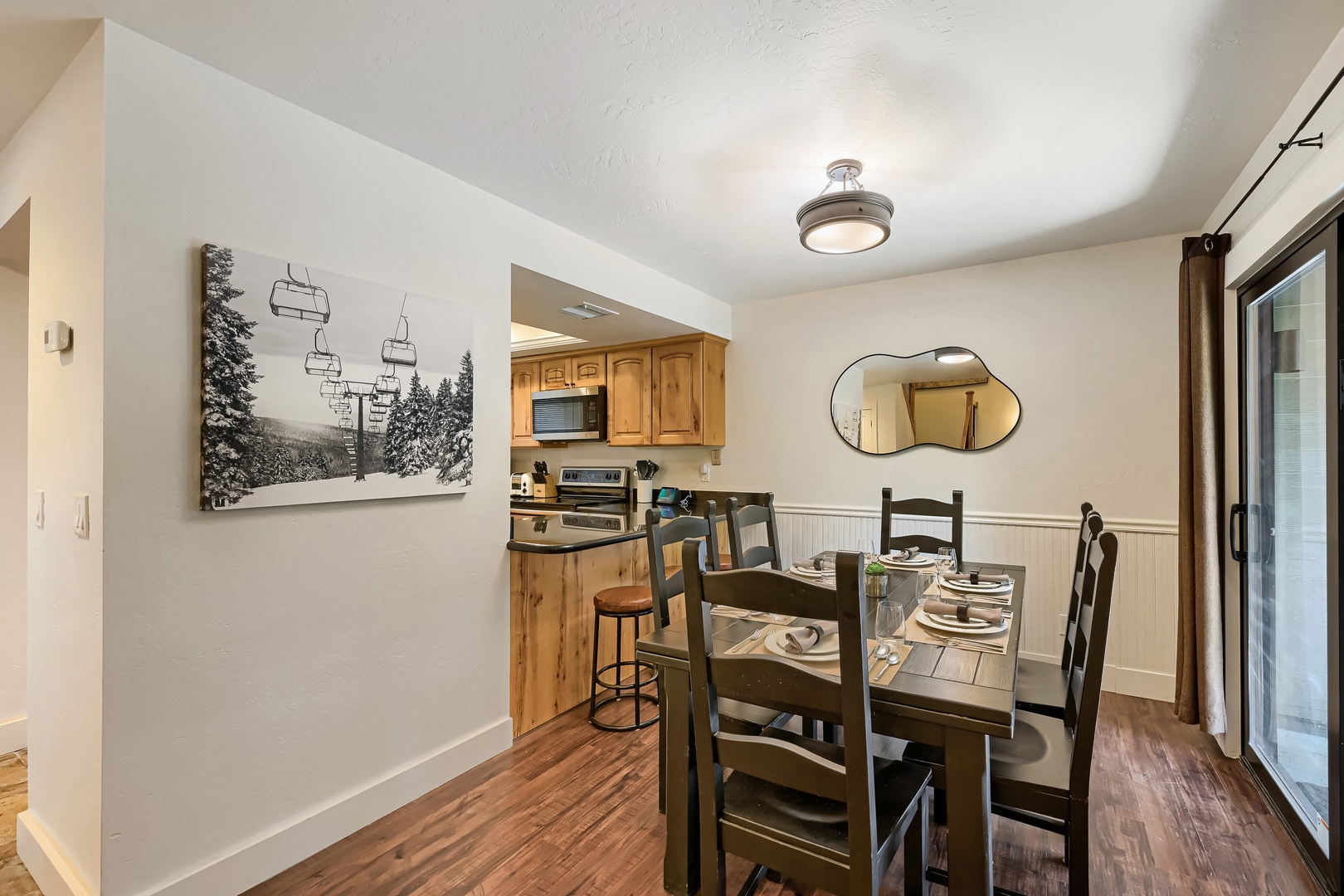 Step into your cozy dining and kitchen space, where warm wood tones and ski-inspired art create a welcoming mountain retreat after a day of adventure.