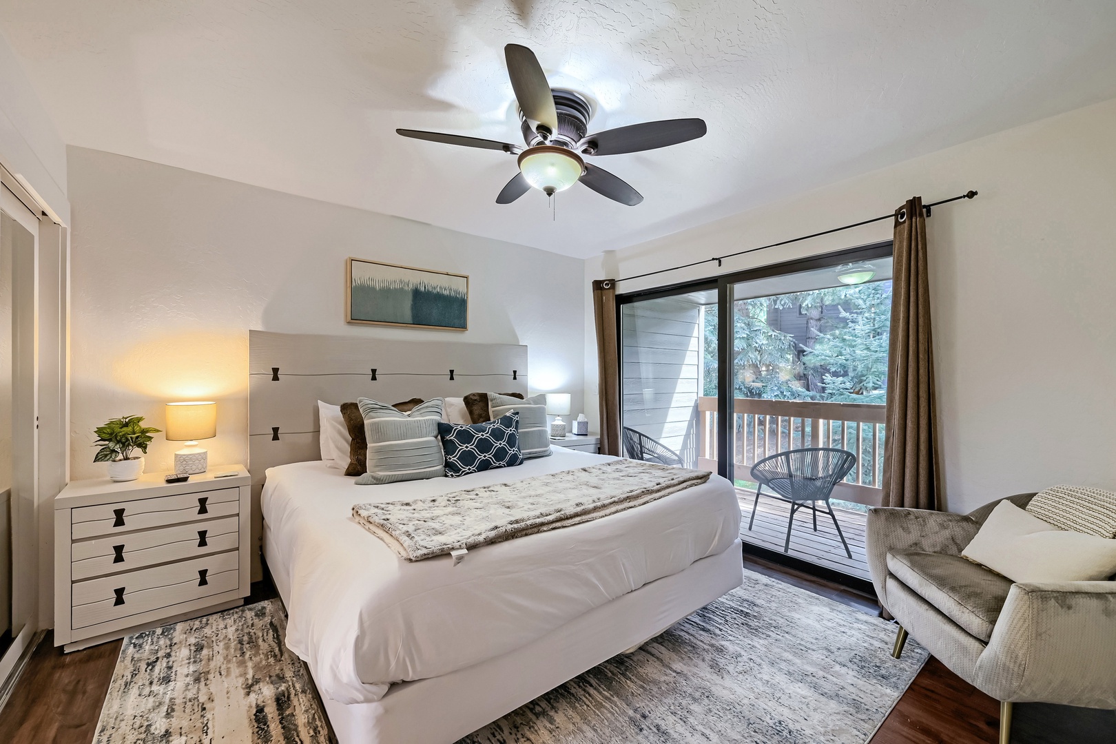 Drift off in your cozy bedroom, where soft linens invite restful sleep and a private balcony opens to peaceful forested surroundings just beyond the glass doors.