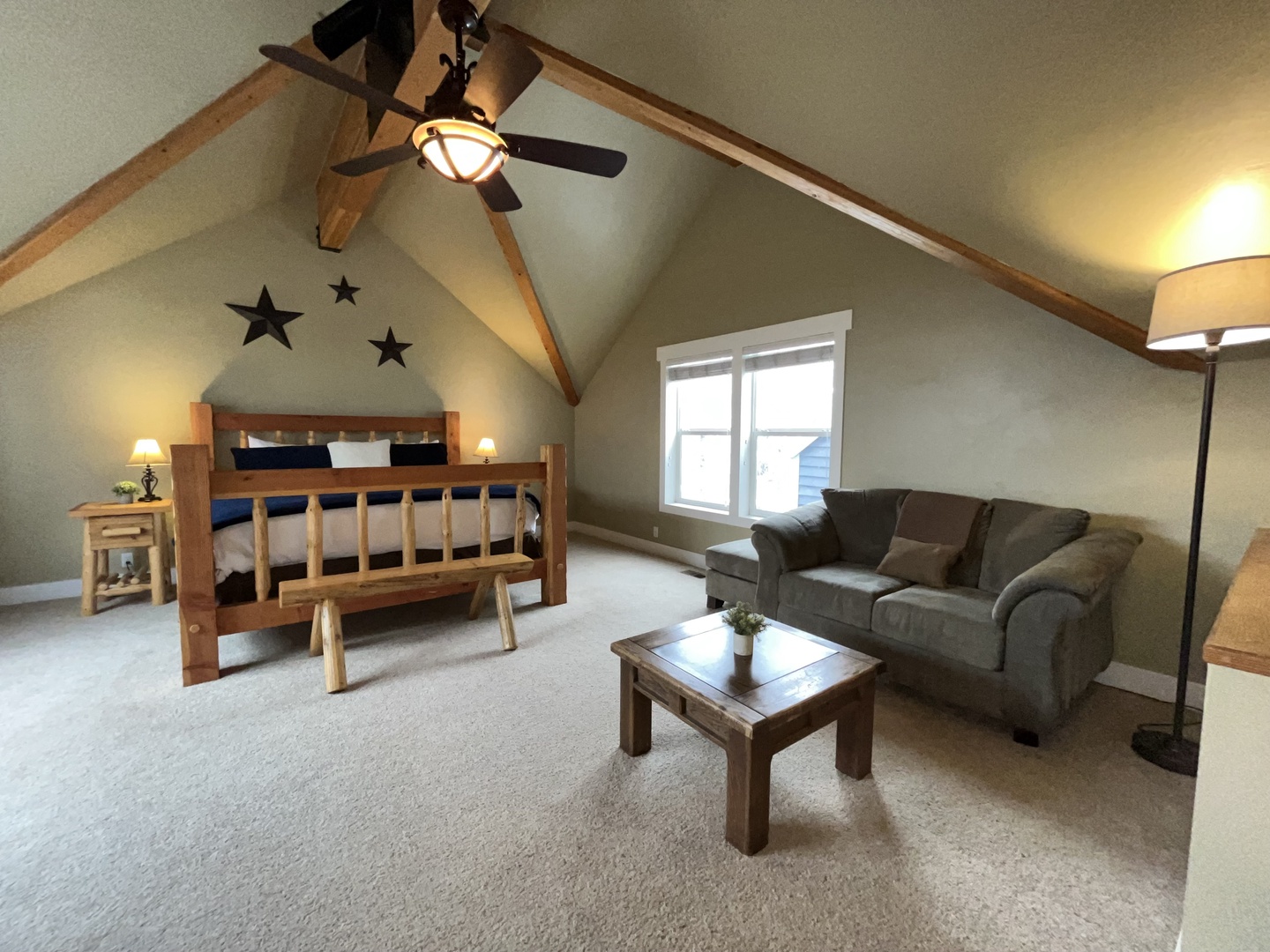 Unwind in your cozy loft retreat featuring rustic bunk beds and plush seating under soaring vaulted ceilings with charming star accents.