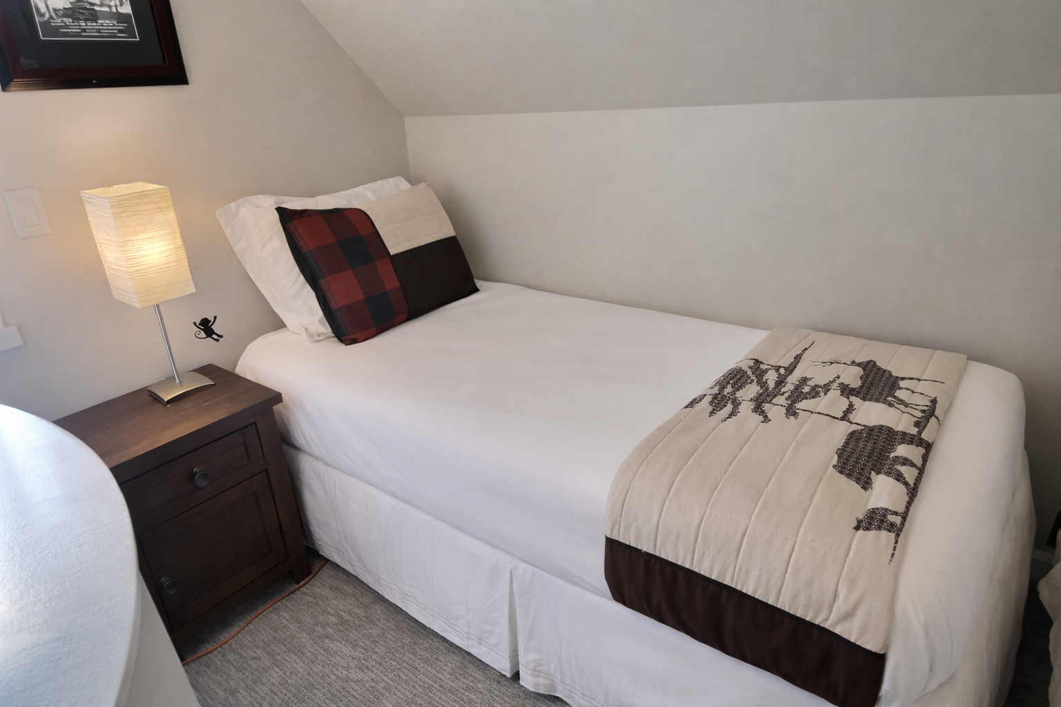 Unwind in the cozy attic bedroom, featuring a large smart TV, dedicated storage, and a comfortable bed under charming sloped ceilings.