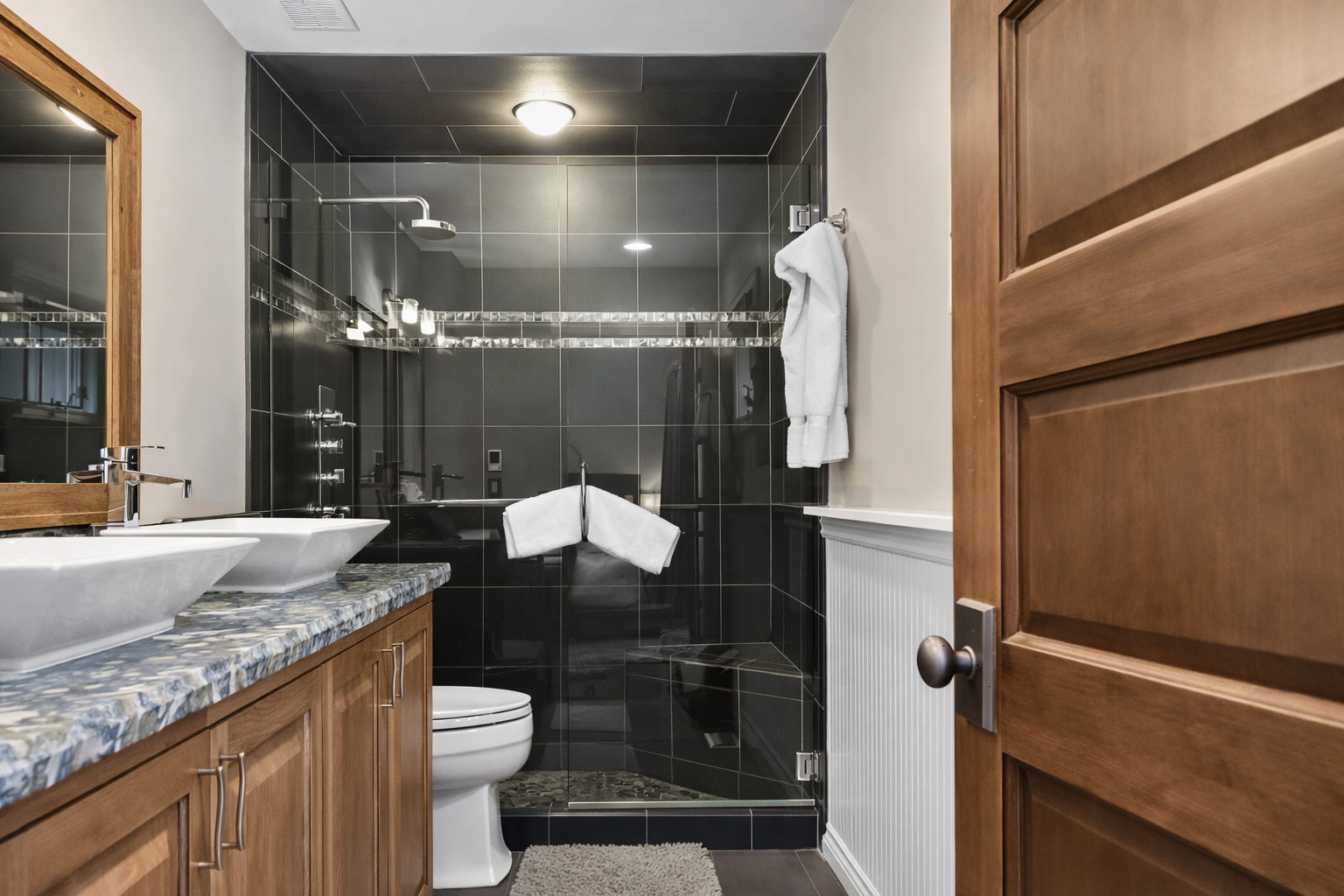 Your private bathroom features elegant dark tiling, a spacious walk-in shower, and beautiful granite countertops for your comfort.