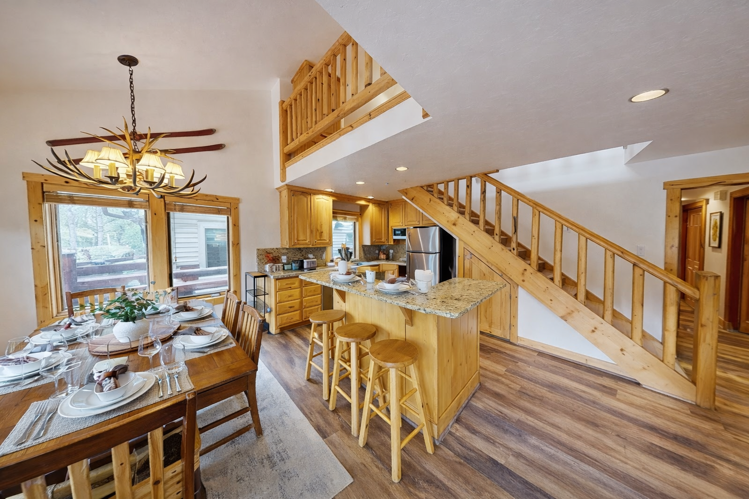 Your open-concept retreat blends rustic charm with modern comfort, featuring warm wood throughout and a stunning antler chandelier.