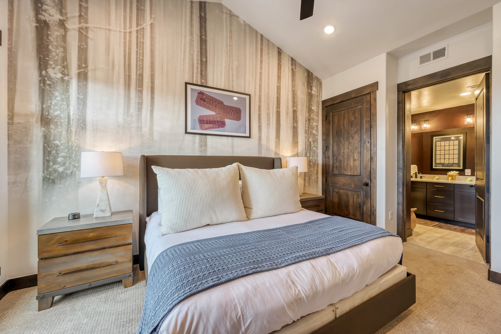 Sink into soft linens and mountain-lodge charm in your private retreat, where rustic wood accents and a serene forest mural create the perfect escape after a day of adventure.