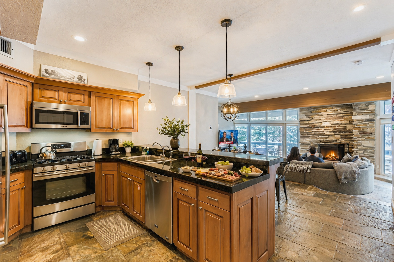 Warm up after a day on the slopes in this inviting open-concept great room featuring a fully stocked kitchen, cozy stone fireplace, and comfortable gathering space perfect for après-ski nights, family meals, and movie time together.