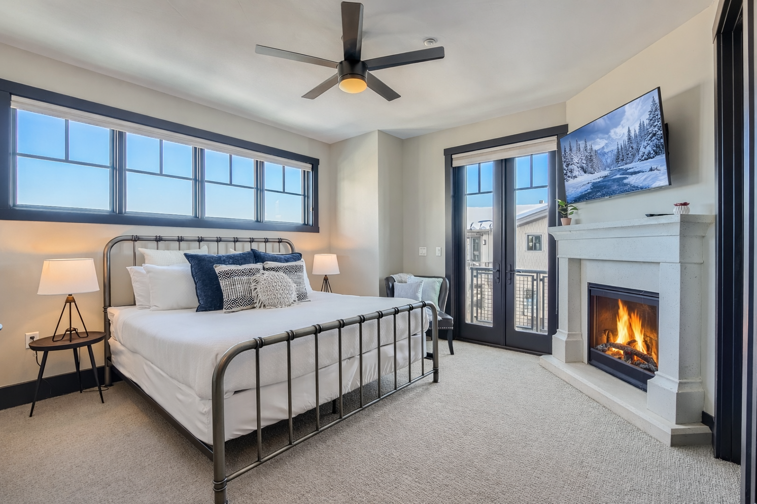 Relax in this bright master suite featuring a plush king bed and a cozy fireplace. Large windows and a private balcony offer serene views for a perfect mountain retreat.