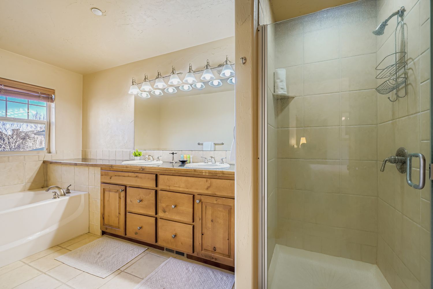Your private bathroom features a relaxing soaking tub, spacious walk-in shower, and double vanity with warm wood cabinetry - perfect for unwinding after your adventures.