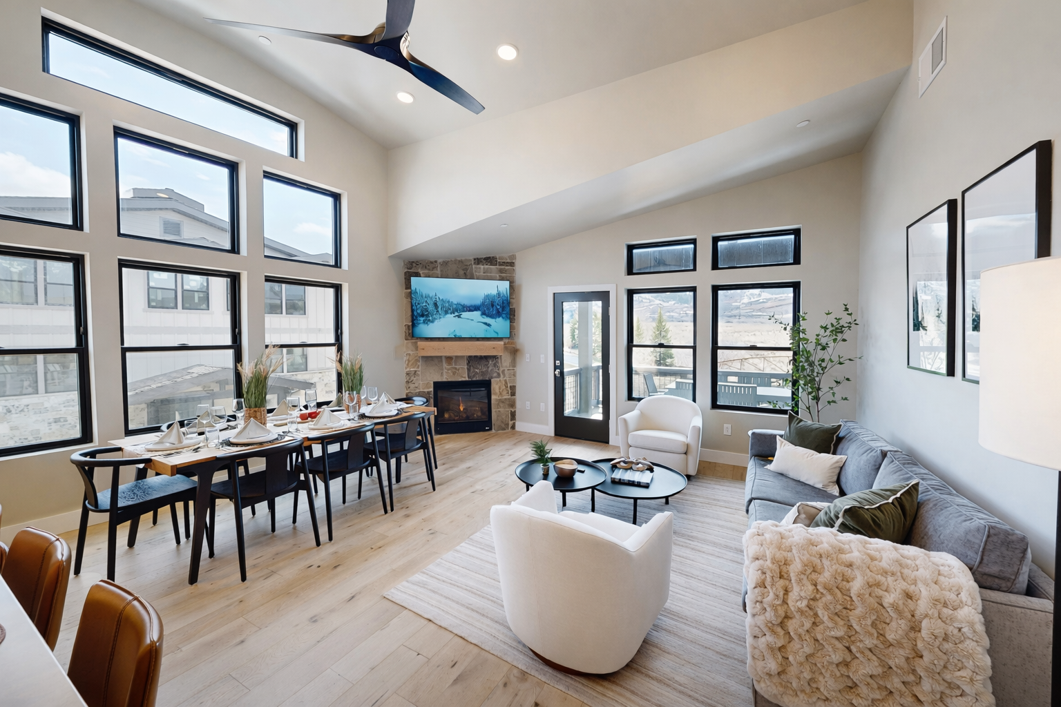 Relax in this bright, airy living room featuring soaring vaulted ceilings and a cozy stone fireplace. Large windows flood the space with natural light, while the open-concept design is perfect for family gatherings.