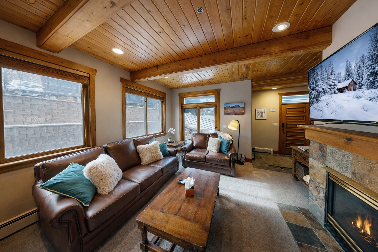 Sink into your plush sectional sofa while the fireplace crackles and natural light streams through wooden blinds in this cozy mountain retreat.