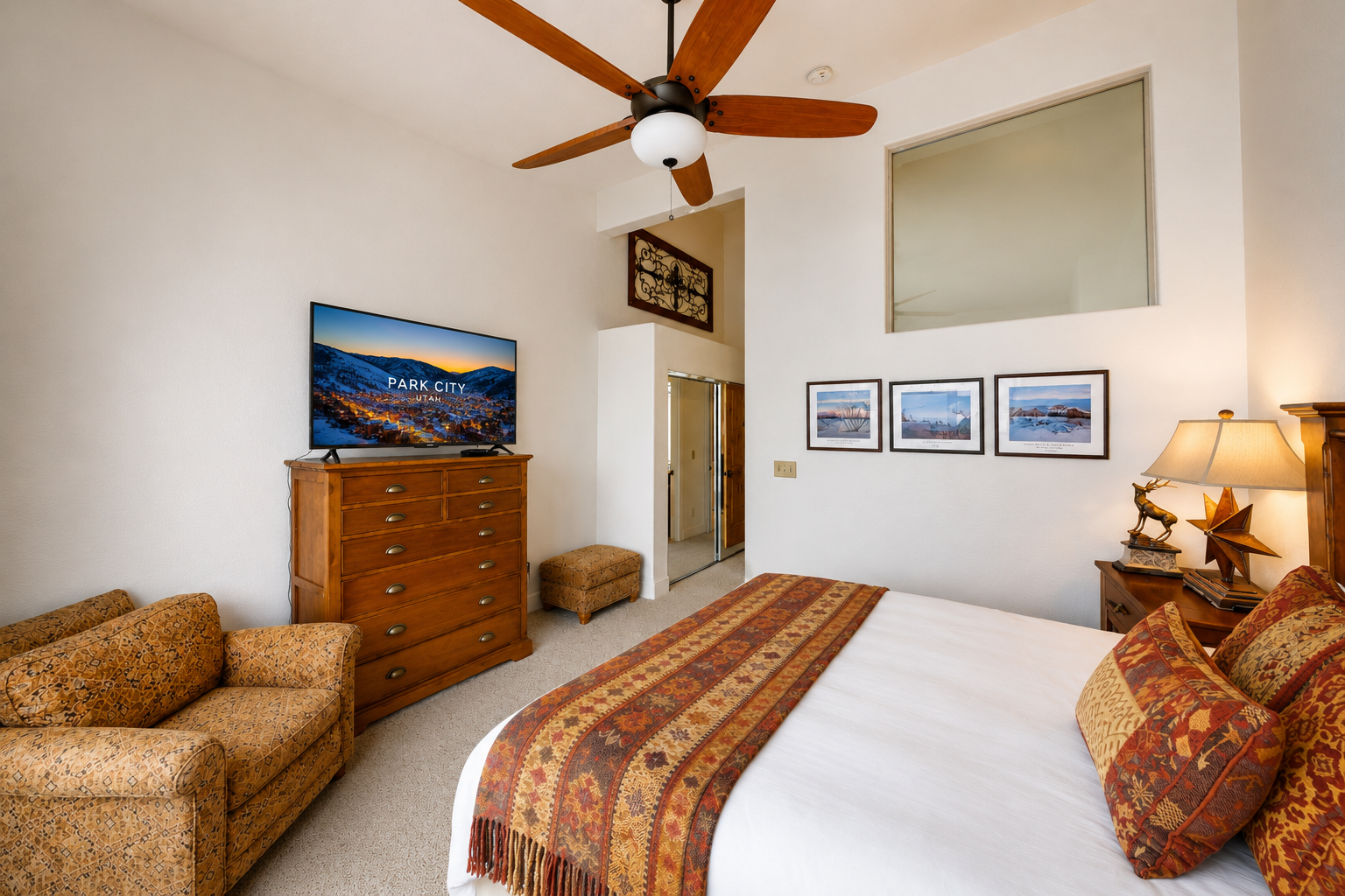 Unwind in your cozy bedroom with plush linens, a ceiling fan, and mountain-view art—your perfect retreat after a day exploring Park City.