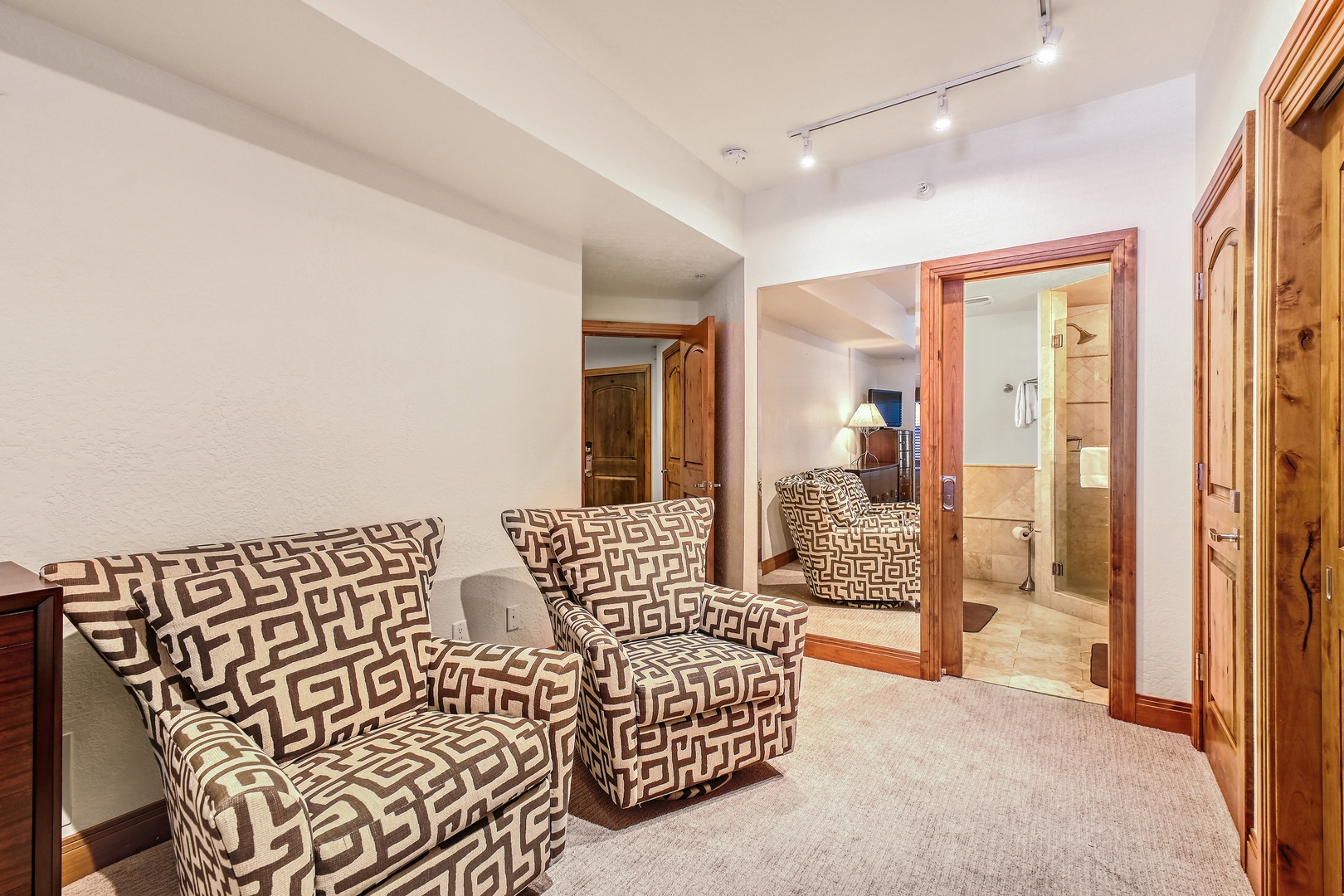 Unwind in your cozy seating area with stylish geometric chairs and warm wood accents throughout.