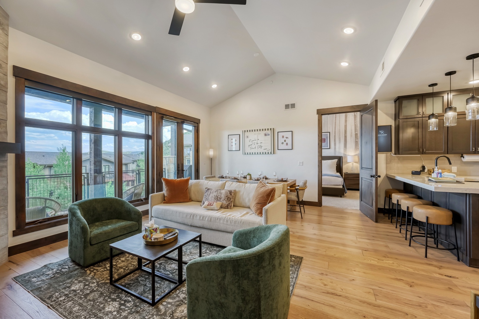 Step into your inviting open-concept space with vaulted ceilings, modern kitchen, cozy living area, and abundant natural light pouring through expansive windows.