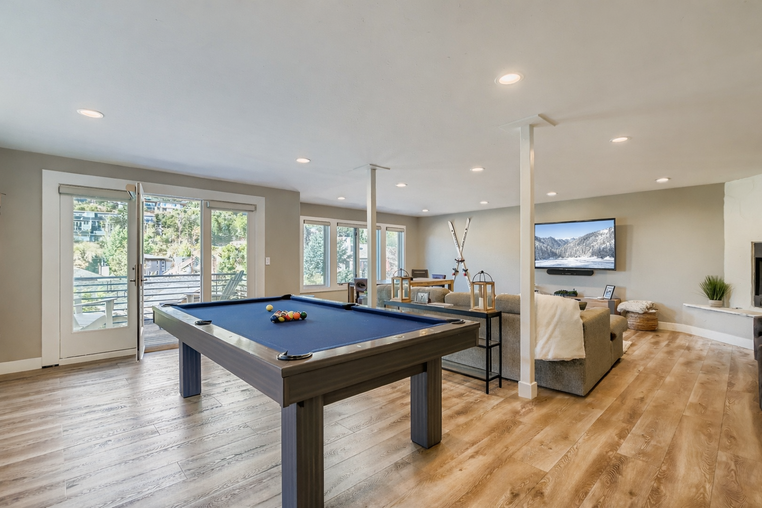 Your entertainment awaits in this spacious game room featuring a pristine pool table, cozy seating, and stunning mountain views through expansive windows.