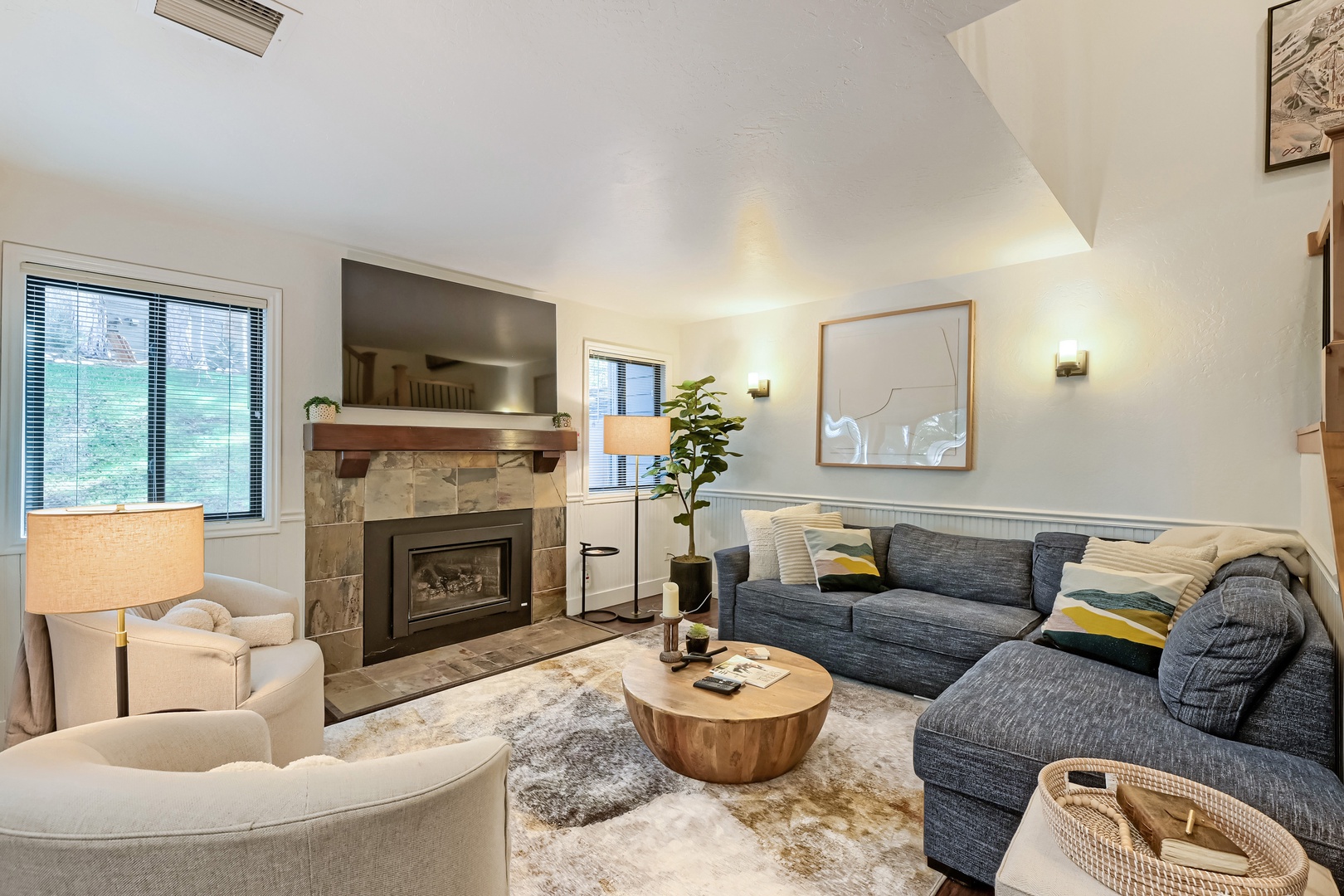 Unwind in this beautifully designed living space with plush seating, a warm fireplace, and natural light streaming through the windows—perfect for your mountain retreat.