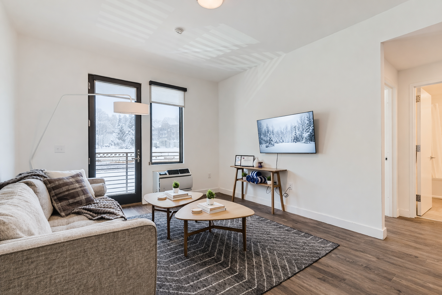 Relax in this modern living room featuring a comfortable sofa and a smart TV. Enjoy the bright space and views of the surrounding area during your Park City stay.