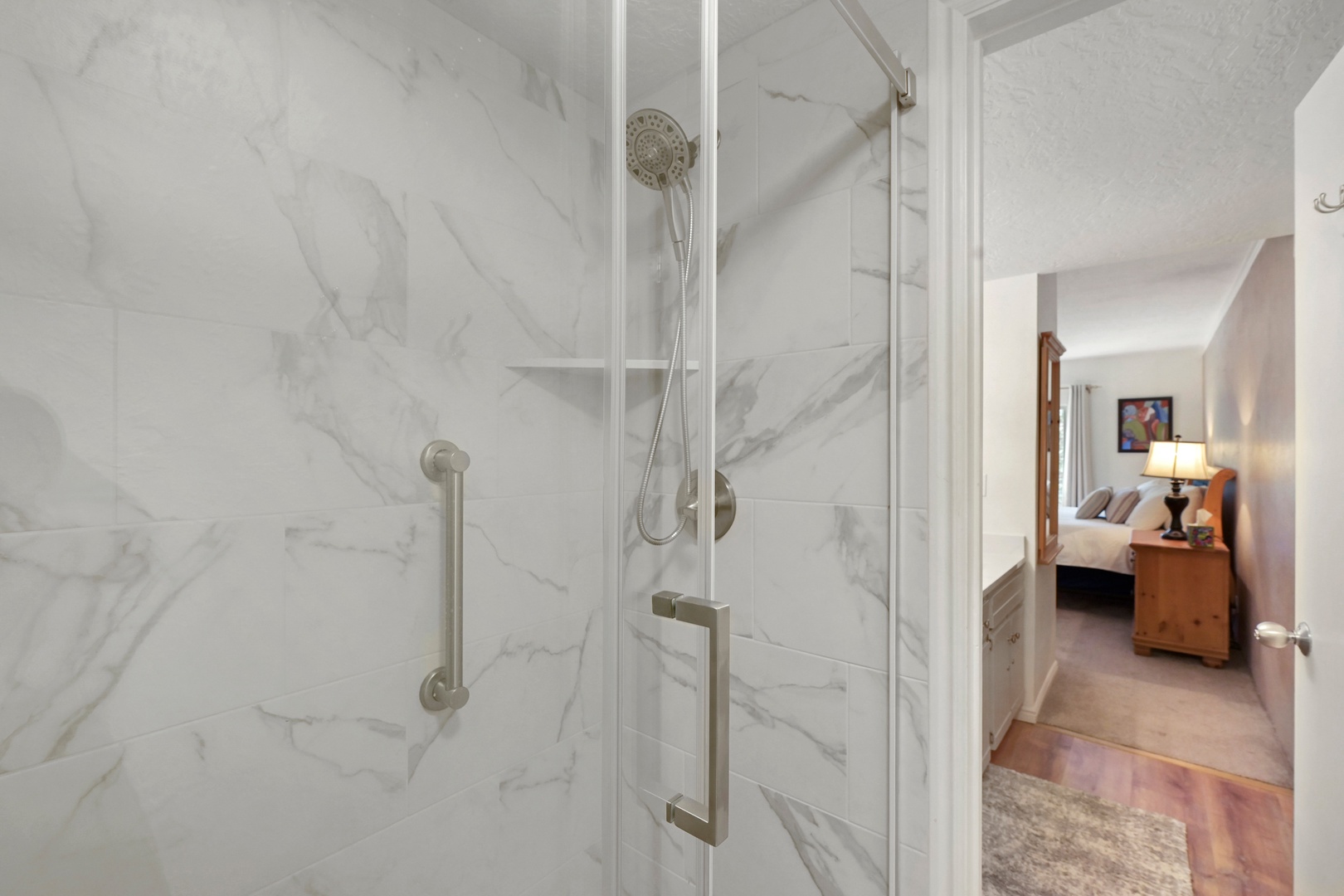 Step into your private spa-like shower with gleaming marble-look tile and accessible grab bars, where relaxation awaits after a day of adventure.