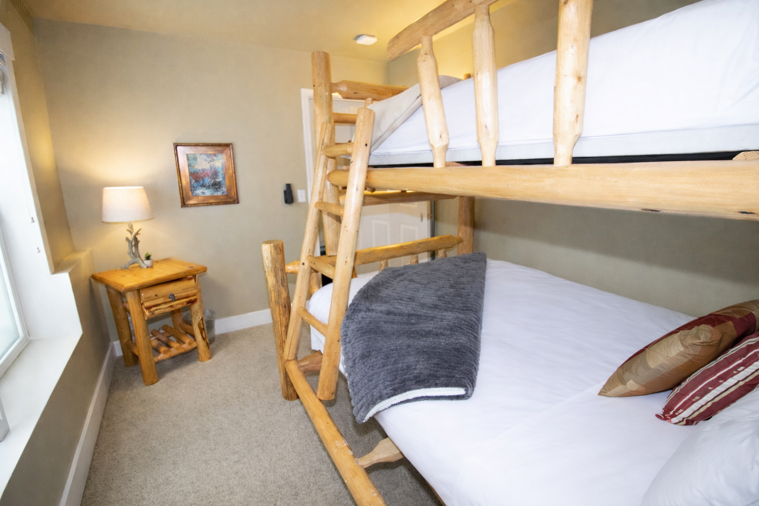 Perfect for families, this bunk room features a sturdy, hand-crafted log bed with a twin over full layout. Bright, natural light and plush carpeting create a cozy, fun retreat.