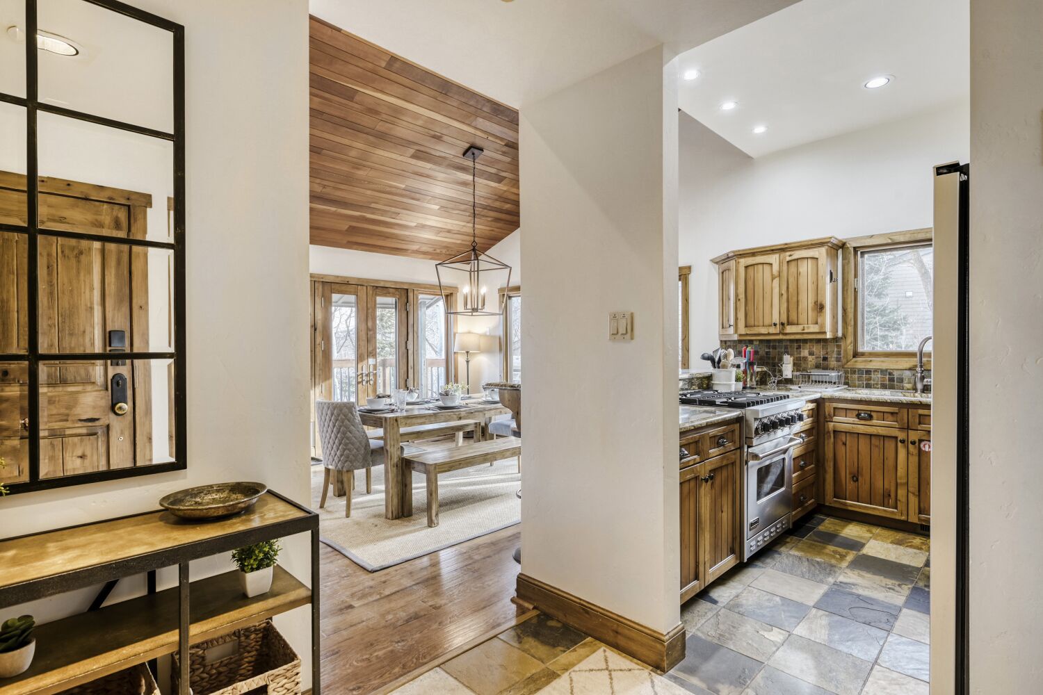 Step into this warm, rustic kitchen where wood cabinets and stone floors create a cozy mountain retreat atmosphere for your culinary adventures.