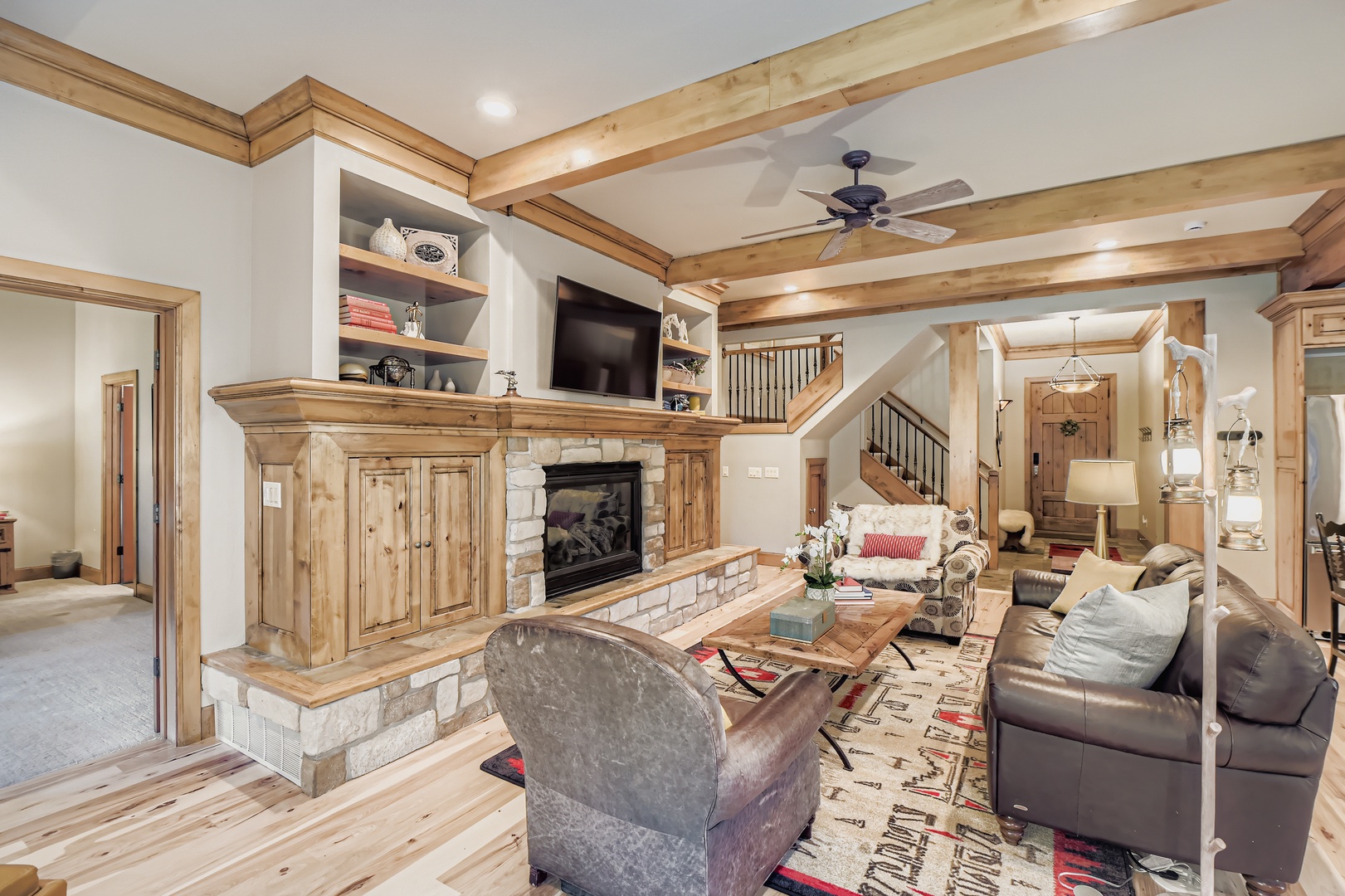 Settle into your cozy living room with warm wood beams overhead, a crackling stone fireplace, and plush seating perfect for relaxing evenings together after a day of mountain adventures.