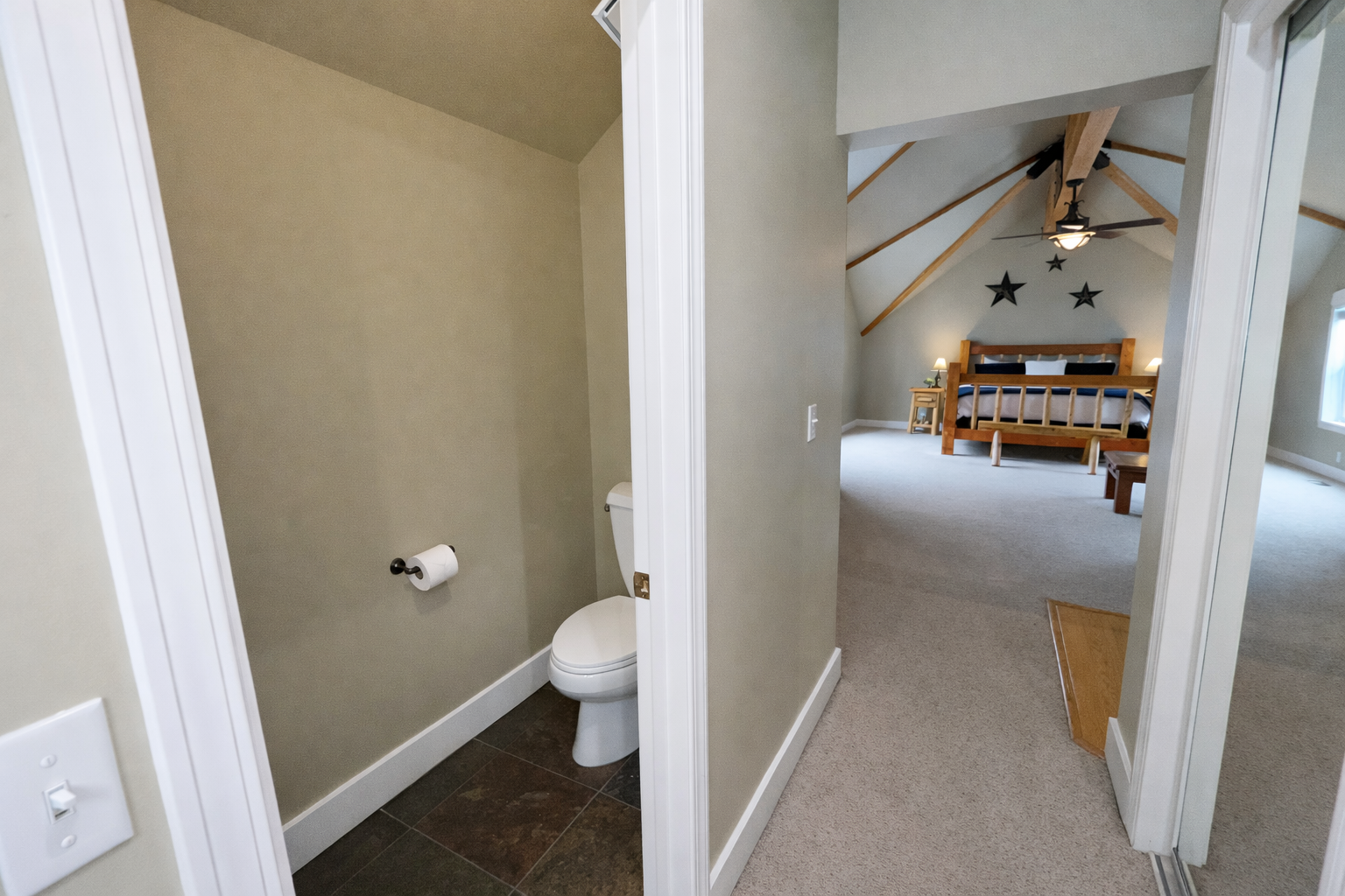 This private half-bath is conveniently located just off the spacious master bedroom. It features dark tile flooring, neutral-toned walls, and sleek black hardware for a clean, modern look.