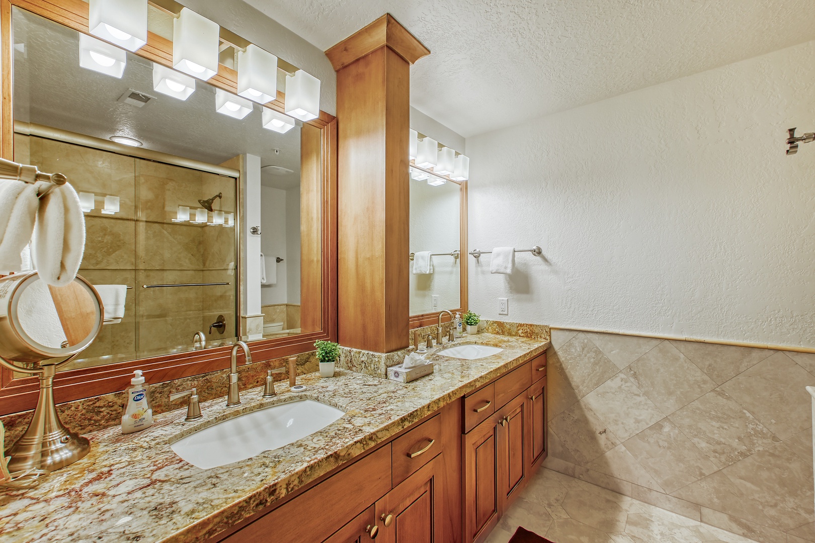 Your elegant master bathroom features dual vanities with granite countertops, warm wood cabinetry, and a luxurious walk-in shower.